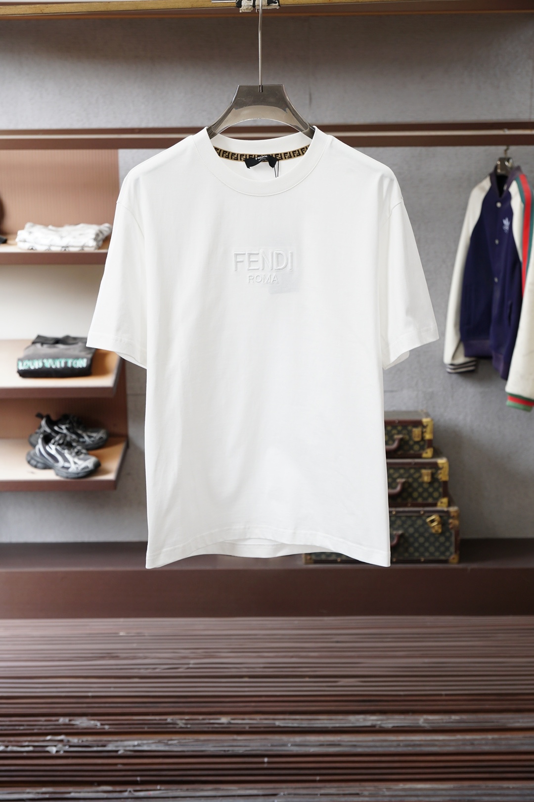 NO:733566,, Fendi (Fendi) white FF logo short-sleeved T-shirt is a classic light luxury basic model of the brand. The core features are as follows 1. The brand logo collar is edged with Fendi’s classic presbyopic webbing, and the brand’s iconic FF monogram badge is on the chest of the body. It is designed with a brown and black contrasting presbyopic pattern, which is highly recognizable and not exaggerated. 2.  The oversize version with loose shoulders and loose shoulders is suitable for many body shapes; the fabric is high-count combed cotton, which has both stiffness and breathability, and is the core material standard for luxury basic T-shirts. 3. Craftsmanship details The FF badge uses embroidery patch technology, with neat edges that are not easy to fall off; the collar is reinforced and hemmed to effectively avoid deformation after long-term wear, reflecting the brand's craftsmanship. 2. Brand and product positioning 1.  Design background The FF logo evolved from Fendi's iconic 'double F' presbyopia. After modern and simplified design, it has become the core visual symbol of the brand's youthfulness and trendiness, breaking the heavy feeling of traditional luxury goods. 2. The market attribute belongs to Fendi's entry-level light luxury items. It is a popular choice among fashion enthusiasts and entry-level consumers of luxury goods in China. It has both brand recognition and daily practicality. 3.  Style adaptation not only retains Fendi's high-end genes, but also can be perfectly integrated into various styles such as street, casual, light and trendy. It is a typical representative item of 'high luxury fashion branding'.,,fendi,fendi,versace,T-shirt,tees,t-shirt,19860909,Fendi（芬迪） 白色FF标识短袖T恤,属于品牌经典轻奢基础款,核心特征如下 1. 品牌标识领口内侧有芬迪经典的老花织带包边,衣身胸口位置是品牌标志性的FF字母组合徽章,采用棕黑撞色的老花图案拼接设计,辨识度极高且不浮夸. 2. 版型与面料宽松落肩的Oversize版型,适配多身形；面料为高支精梳纯棉,挺括度与透气性兼顾,是奢侈品基础款T恤的核心用料标准. 3. 工艺细节FF徽章采用刺绣贴布工艺,边缘工整不易脱落；领口做了加固包边处理,有效避免久穿变形,体现品牌工艺水准. 二、品牌与产品定位 1. 设计背景FF标识由芬迪标志性的“双F”老花演变而来,经现代简约化设计后,成为品牌年轻化、潮牌化的核心视觉符号,打破了传统奢侈品的厚重感. 2. 市场属性属于芬迪入门级轻奢单品,国内专是潮流爱好者与奢侈品入门消费者的热门选择,兼具品牌辨识度与日常实用性. 3. 风格适配既保留了芬迪的高端基因,又能完美融入街头、休闲、轻潮等多种穿搭风格,是“高奢潮牌化”的典型代表单品.,,fendi,fendi,versace,T-shirt,tees，t-shirt,,Men's clothing