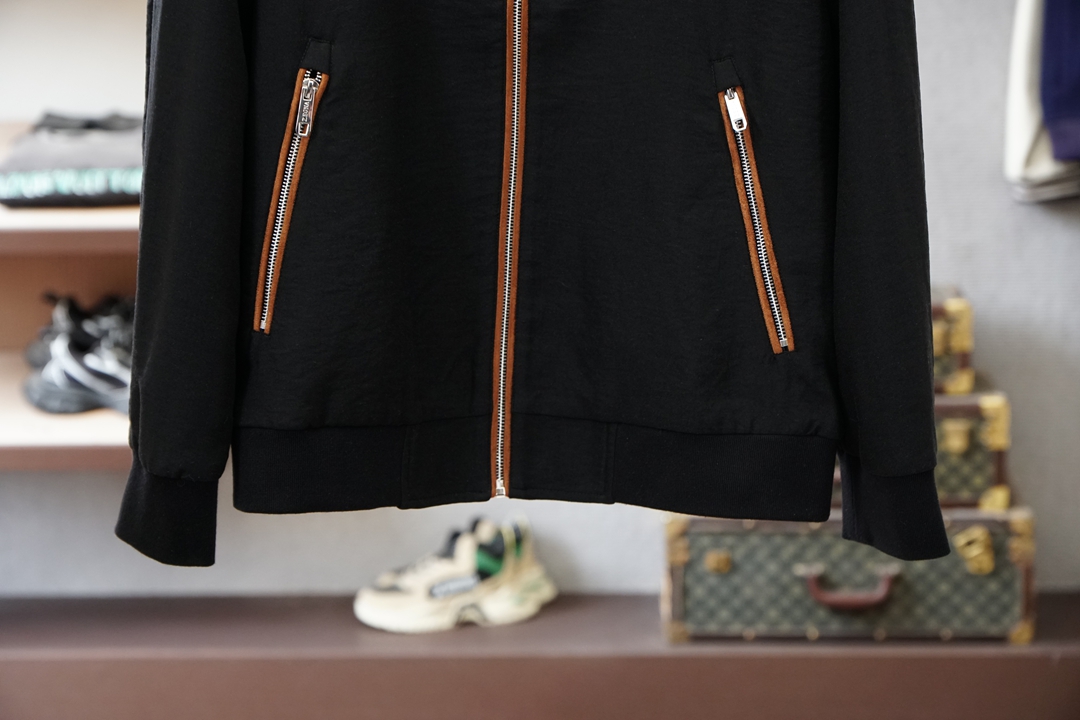 杰尼亚经典黑色立领外套，简约商务与休闲感兼具。整体黑色基底搭配棕色撞色包边，拉链、口袋线条精致高级，胸前