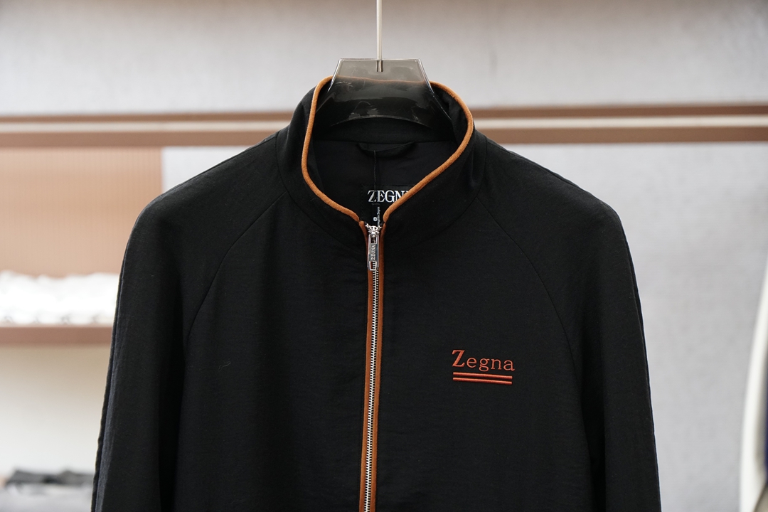 杰尼亚经典黑色立领外套，简约商务与休闲感兼具。整体黑色基底搭配棕色撞色包边，拉链、口袋线条精致高级，胸前