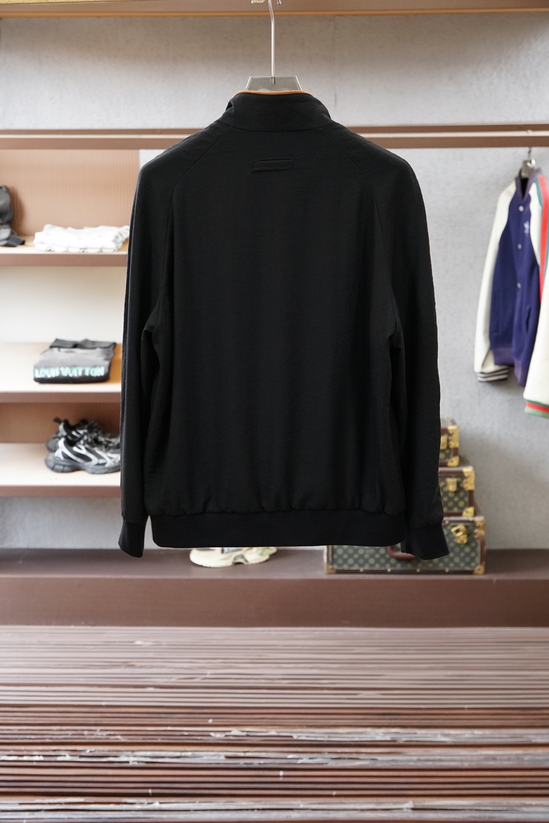 杰尼亚经典黑色立领外套，简约商务与休闲感兼具。整体黑色基底搭配棕色撞色包边，拉链、口袋线条精致高级，胸前