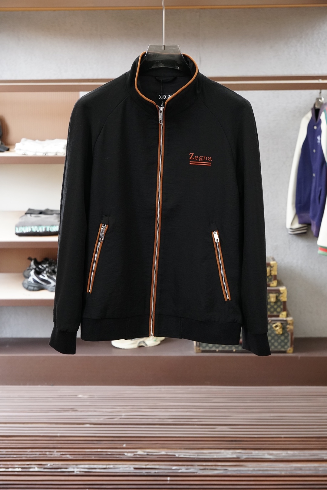 杰尼亚经典黑色立领外套，简约商务与休闲感兼具。整体黑色基底搭配棕色撞色包边，拉链、口袋线条精致高级，胸前