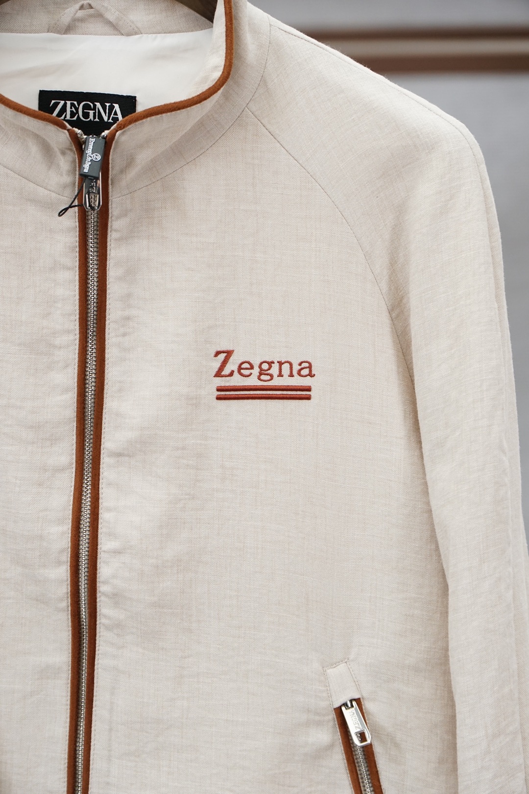 杰尼亚经典黑色立领外套，简约商务与休闲感兼具。整体黑色基底搭配棕色撞色包边，拉链、口袋线条精致高级，胸前