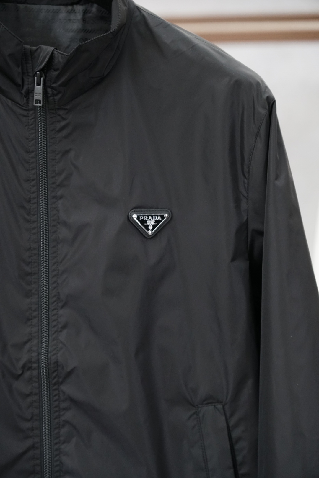 普拉达经典深灰立领轻薄外套，极简高级感拉满。哑光顺滑面料，轻便透气，日常防风又好穿。胸前标志性三角徽标，