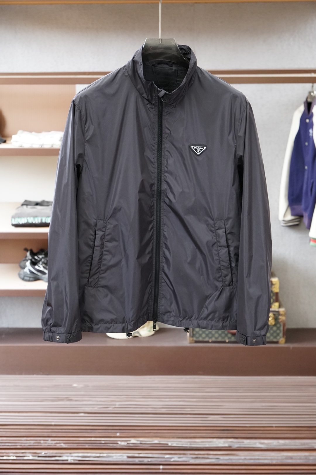 普拉达经典深灰立领轻薄外套，极简高级感拉满。哑光顺滑面料，轻便透气，日常防风又好穿。胸前标志性三角徽标，