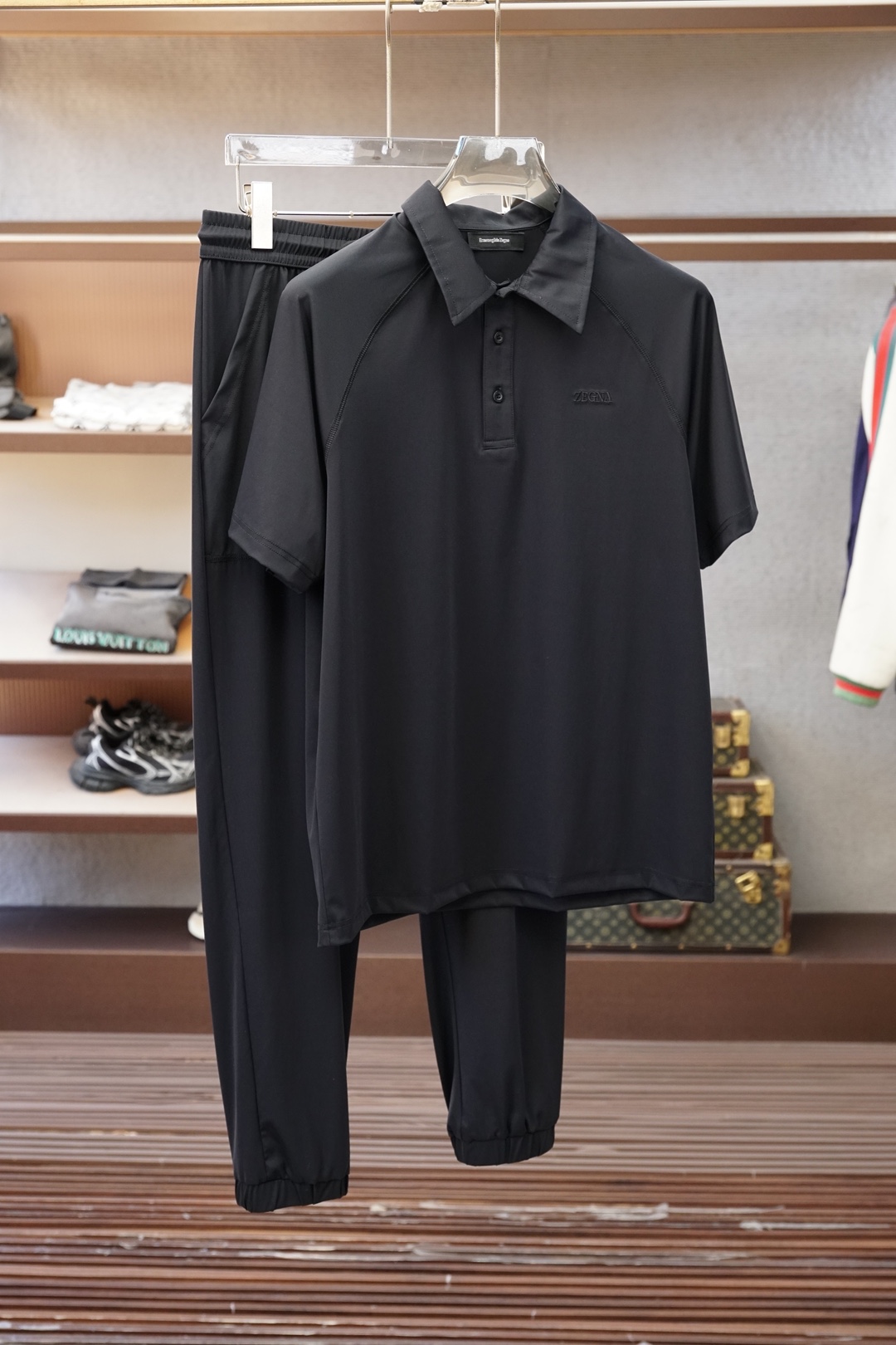 NO:833497,, Zegna/  , the 2026 spring and summer new men's light luxury casual suit combines Italian craftsmanship with contemporary sports aesthetics. The top is a short-sleeved half-zip Polo, with neat lapels that show spirit, and a half- placket design that adds a casual layer; the exquisite embroidered badge on the chest is the finishing touch and is low-key.  Brand style. The bottoms are loose straight-leg sports trousers with an elastic waistband and drawstring, which are comfortable and not flattering on the figure. The side zipper pockets are both practical and fashionable. The same embroidery on the trouser legs echoes the top, and the overall coordination is high-end. The fabric is made of Italian combed cotton, which is soft to the touch.  Soft and breathable, draped and stylish, it is refreshing and not stuffy to wear in spring and summer, and it still maintains its texture after washing. In terms of style, it breaks the traditional boundaries between business and sports. It is suitable for weekend outings and light sports scenes, and can also easily handle urban leisure commuting, showing a calm and confident look.  Gentleman style. The whole outfit is simple but not simple, and the details are full of ingenuity. It is a must-have item for modern men's wardrobe who pursues quality and style. M-4XL (model weighs 173,143 pounds, upper body size L),,zegna,T-shirt,19860909,杰尼亚/ ,2026春夏新品男士轻奢休闲套装,将意式工艺与当代运动美学融合.上衣为短袖半拉链Polo,翻领利落显精神,半开襟设计增添随性层次；胸前精致刺绣徽章点睛,低调彰显品牌格调.下装是宽松直筒运动长裤,松紧腰头配抽绳,舒适不挑身形,侧边拉链口袋兼顾实用与潮流感,裤腿同款刺绣呼应上衣,整体协调高级.面料选用意大利原产精梳棉,触感柔软透气,垂坠有型,春夏穿着清爽不闷热,水洗后依然保持质感.风格上,它打破传统商务与运动的界限,既适配周末郊游、轻运动场景,也能轻松驾驭都市休闲通勤,展现从容自信的绅士型格.整套穿搭简约却不简单,细节处尽显匠心,是追求品质与风格的现代男士衣橱必备单品.M-4XL（模特173,143斤上身L码）,,zegna,T-shirt,,Men's clothing