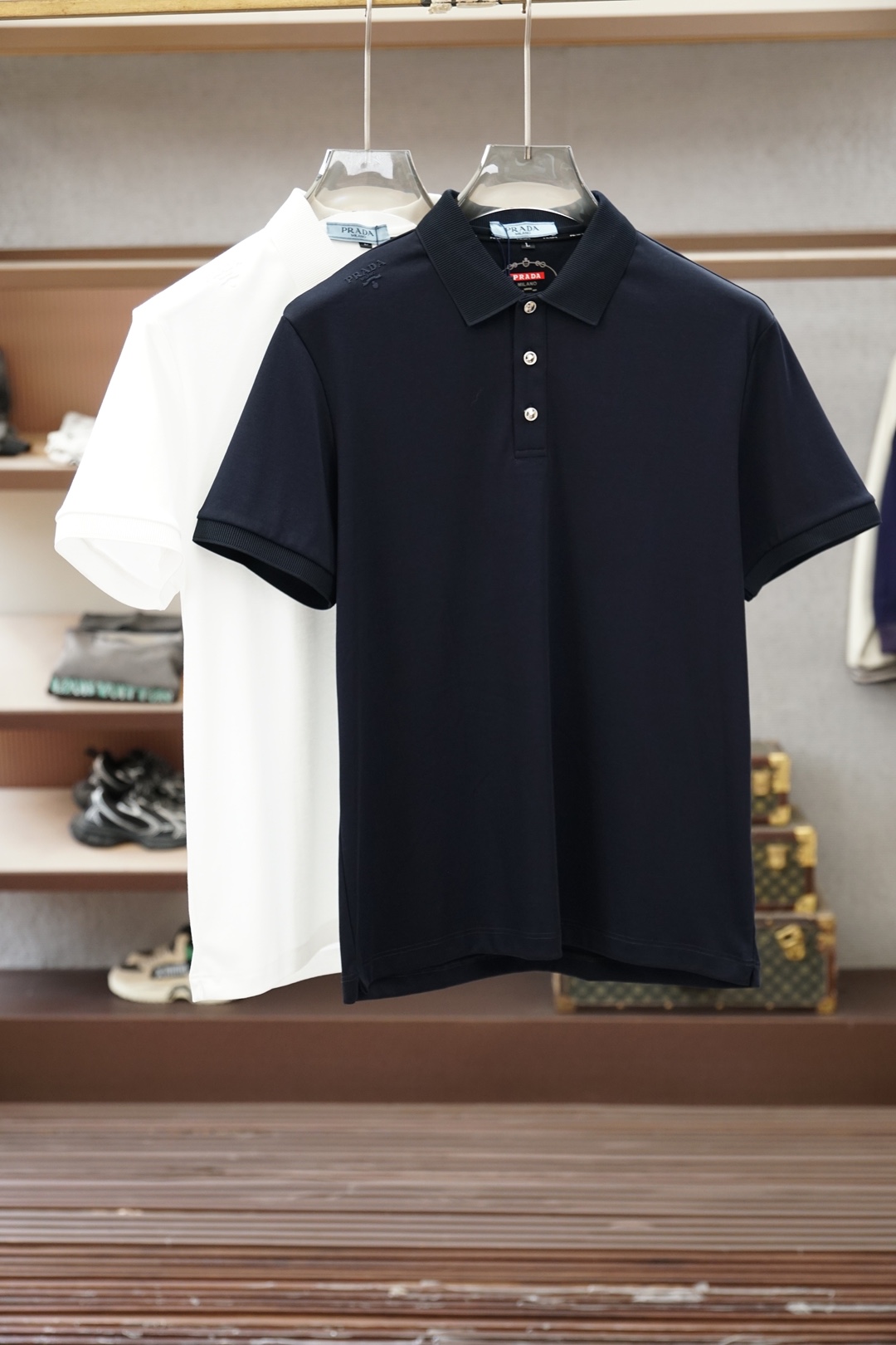 NO:843406,Prada/2026ss new product launched, classic refreshed high-end pique Polo shirt  The fabric is made of black technology, giving you a comfortable and luxurious feeling. It is made of double-sided pique mesh fabric. The three-dimensional pique texture is intertwined with warp and weft. It has a breathable mesh structure. It keeps the skin dry at all times when wearing it in summer, saying goodbye to stuffiness and stickiness. The double-sided weaving process makes the fabric more stiff and wear-resistant, and can be worn for a long time.  It is not easily deformed and can be worn with any outfit. It is neat and stylish. It is anti-wrinkle and easy to care for, making it the best choice for business trips. The classic Polo collar is matched with contrasting striped piping, and the neat lines outline the neck, giving it a sense of business formality. The exquisite embroidery logo on the left chest is a low-key statement.  The brand style is unobtrusive yet self-recognizable; whether worn alone for casual everyday use or worn under a suit for a business elite look, it can easily hold up in various scenarios. From fabric selection to cutting and sewing, every process follows the production standards of big brands, and three-dimensional tailoring fits perfectly.  The body shape is not tight, taking into account comfort and shape aesthetics. The fusion of double-sided pique texture and classic design makes this Polo shirt not only a piece of clothing, but also a business card of your taste. Sizes M-3XL, prada, prada, business  suit,19860909Prada普拉达/2026ss新品上线 经典焕新高端珠地Polo衫 面料黑科技,穿出来的舒适奢感,采用双面珠地网眼面料打造,经纬交织的立体珠地肌理,自带透气网孔结构,夏日穿着时刻保持肌肤干爽,告别闷热黏腻；双面织造工艺让面料更挺括耐磨,久穿不易变形,随手一搭都是利落型格,抗皱易打理的特性,更是商旅出行的不二之选.经典Polo领搭配撞色条纹滚边,利落线条勾勒颈部轮廓,商务正式感拉满；左胸精致刺绣标识,低调彰显品牌格调,不张扬却自带辨识度；无论是单穿打造休闲日常,还是内搭西装诠释商务精英范,都能轻松hold住各种场景.从面料甄选到剪裁缝制,每一道工序都遵循大牌制作标准,立体剪裁贴合身形不紧绷,兼顾舒适与版型美感.双面珠地的质感与经典设计的融合,让这件Polo衫不止是一件服饰,更是你的品位名片.尺码M-3XL,,prada,prada,business suit,,Men's clothing