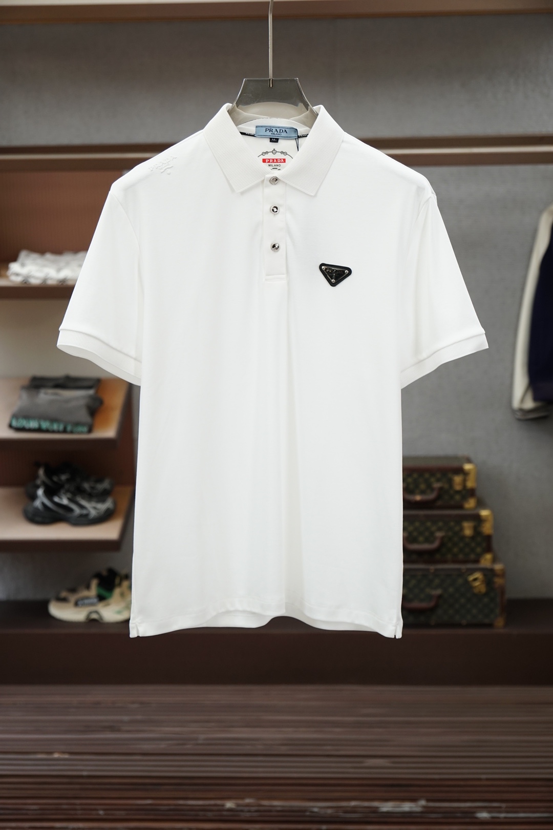 NO:843425,Prada/2026ss new product launched, classic refreshed high-end pique Polo shirt  The fabric is made of black technology, giving you a comfortable and luxurious feeling. It is made of double-sided pique mesh fabric. The three-dimensional pique texture is intertwined with warp and weft. It has a breathable mesh structure. It keeps the skin dry at all times when wearing it in summer, saying goodbye to stuffiness and stickiness. The double-sided weaving process makes the fabric more stiff and wear-resistant, and can be worn for a long time.  It is not easily deformed and can be worn with any outfit. It is neat and stylish. It is anti-wrinkle and easy to care for, making it the best choice for business trips. The classic Polo collar is matched with contrasting striped piping, and the neat lines outline the neck, giving it a sense of business formality. The exquisite embroidery logo on the left chest is a low-key statement.  The brand style is unobtrusive yet self-recognizable; whether worn alone for casual everyday use or worn under a suit for a business elite look, it can easily hold up in various scenarios. From fabric selection to cutting and sewing, every process follows the production standards of big brands, and three-dimensional tailoring fits perfectly.  The body shape is not tight, taking into account comfort and shape aesthetics. The fusion of double-sided pique texture and classic design makes this Polo shirt not only a piece of clothing, but also a business card of your taste. Sizes M-3XL, prada, prada, business  suit,19860909Prada普拉达/2026ss新品上线 经典焕新高端珠地Polo衫 面料黑科技,穿出来的舒适奢感,采用双面珠地网眼面料打造,经纬交织的立体珠地肌理,自带透气网孔结构,夏日穿着时刻保持肌肤干爽,告别闷热黏腻；双面织造工艺让面料更挺括耐磨,久穿不易变形,随手一搭都是利落型格,抗皱易打理的特性,更是商旅出行的不二之选.经典Polo领搭配撞色条纹滚边,利落线条勾勒颈部轮廓,商务正式感拉满；左胸精致刺绣标识,低调彰显品牌格调,不张扬却自带辨识度；无论是单穿打造休闲日常,还是内搭西装诠释商务精英范,都能轻松hold住各种场景.从面料甄选到剪裁缝制,每一道工序都遵循大牌制作标准,立体剪裁贴合身形不紧绷,兼顾舒适与版型美感.双面珠地的质感与经典设计的融合,让这件Polo衫不止是一件服饰,更是你的品位名片.尺码M-3XL,,prada,prada,business suit,,Men's clothing