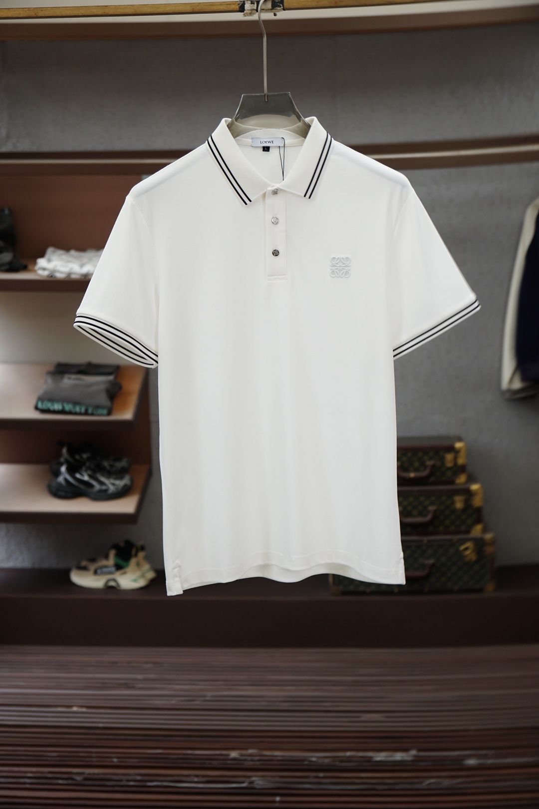 NO:843440,Loewe/2026ss new product launched, classic refreshed high-end pique Polo shirt  The fabric is made of black technology, giving you a comfortable and luxurious feeling. It is made of double-sided pique mesh fabric. The three-dimensional pique texture is intertwined with warp and weft. It has a breathable mesh structure. It keeps the skin dry at all times when wearing it in summer, saying goodbye to stuffiness and stickiness. The double-sided weaving process makes the fabric more stiff and wear-resistant, and can be worn for a long time.  It is not easily deformed and can be worn with any outfit. It is neat and stylish. It is anti-wrinkle and easy to care for, making it the best choice for business trips. The classic Polo collar is matched with contrasting striped piping, and the neat lines outline the neck, giving it a sense of business formality. The exquisite embroidery logo on the left chest is a low-key statement.  The brand style is unobtrusive yet self-recognizable; whether worn alone for casual everyday use or worn under a suit for a business elite look, it can easily hold up in various scenarios. From fabric selection to cutting and sewing, every process follows the production standards of big brands, and three-dimensional tailoring fits perfectly.  The body shape is not tight, taking into account both comfort and aesthetics. The fusion of double-sided pique texture and classic design makes this Polo shirt not only a piece of clothing, but also a business card of your taste. Sizes M-3XL,,loewe,loewe,business  suit,19860909Loewe罗意威/2026ss新品上线 经典焕新高端珠地Polo衫 面料黑科技,穿出来的舒适奢感,采用双面珠地网眼面料打造,经纬交织的立体珠地肌理,自带透气网孔结构,夏日穿着时刻保持肌肤干爽,告别闷热黏腻；双面织造工艺让面料更挺括耐磨,久穿不易变形,随手一搭都是利落型格,抗皱易打理的特性,更是商旅出行的不二之选.经典Polo领搭配撞色条纹滚边,利落线条勾勒颈部轮廓,商务正式感拉满；左胸精致刺绣标识,低调彰显品牌格调,不张扬却自带辨识度；无论是单穿打造休闲日常,还是内搭西装诠释商务精英范,都能轻松hold住各种场景.从面料甄选到剪裁缝制,每一道工序都遵循大牌制作标准,立体剪裁贴合身形不紧绷,兼顾舒适与版型美感.双面珠地的质感与经典设计的融合,让这件Polo衫不止是一件服饰,更是你的品位名片.尺码M-3XL,,loewe,loewe,business suit,,Men's clothing