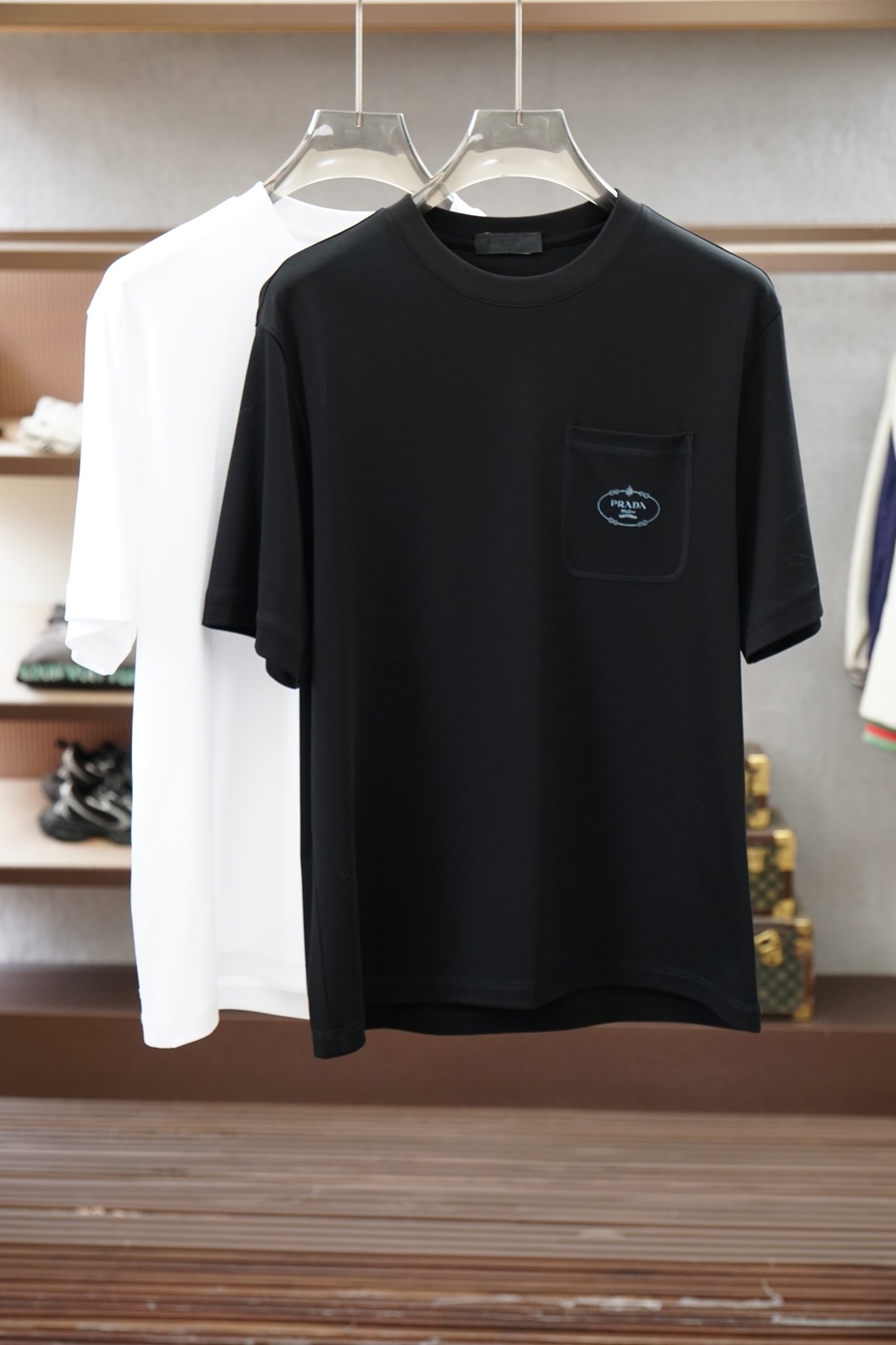 NO:950989,Prada/|| 2026 S/S New new product 1. Color black white 2. Size: M-5XL 3. Style: slightly wide short-sleeved T 4. Ingredients: Lenzing modal fabric, 225 grams in weight, the surface texture of the fabric is fine and smooth, it feels smooth against the skin and crisp and stylish  5. Craftsmanship: The pattern uses classic logo typesetting to make fake pockets, and skin-feeling materials are used for high-temperature pressing. The material feels as soft and skin-friendly as baby skin, prada, prada, T-shirt,19860909Prada普拉达/|| 2026 S/S New 新品 1.颜色黑色 白色 2.尺码:M-5XL 3.版型:微阔短袖T 4.成份:兰精莫代尔面料,225克重,面料表面纹理细腻平整,触感亲肤顺滑且挺括有型 5.工艺:图案用经典logo排版做假口袋,采用肤感材料做高温压烫工艺,材料触感如婴儿肌肤柔软亲肤,,prada,prada,T-shirt,,Men's clothing