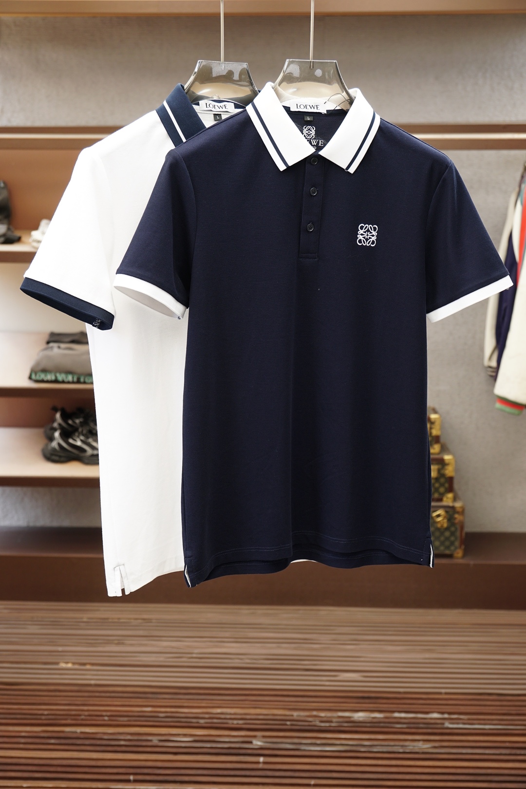 NO:911877,Loewe/2026ss new product launched, classic refreshed high-end pique Polo shirt  The fabric is made of black technology, giving you a comfortable and luxurious feeling. It is made of double-sided pique mesh fabric. The three-dimensional pique texture is intertwined with warp and weft. It has a breathable mesh structure. It keeps the skin dry at all times when wearing it in summer, saying goodbye to stuffiness and stickiness. The double-sided weaving process makes the fabric more stiff and wear-resistant, and can be worn for a long time.  It is not easily deformed and can be worn with any outfit. It is neat and stylish. It is anti-wrinkle and easy to care for, making it the best choice for business trips. The classic Polo collar is matched with contrasting striped piping, and the neat lines outline the neck, giving it a sense of business formality. The exquisite embroidery logo on the left chest is a low-key statement.  The brand style is unobtrusive yet self-recognizable; whether worn alone for casual everyday use or worn under a suit for a business elite look, it can easily hold up in various scenarios. From fabric selection to cutting and sewing, every process follows the production standards of big brands, and three-dimensional tailoring fits perfectly.  The body shape is not tight, taking into account both comfort and aesthetics. The fusion of double-sided pique texture and classic design makes this Polo shirt not only a piece of clothing, but also a business card of your taste. Sizes M-3XL,,loewe,loewe,business  suit,19860909Loewe罗意威/2026ss新品上线 经典焕新高端珠地Polo衫 面料黑科技,穿出来的舒适奢感,采用双面珠地网眼面料打造,经纬交织的立体珠地肌理,自带透气网孔结构,夏日穿着时刻保持肌肤干爽,告别闷热黏腻；双面织造工艺让面料更挺括耐磨,久穿不易变形,随手一搭都是利落型格,抗皱易打理的特性,更是商旅出行的不二之选.经典Polo领搭配撞色条纹滚边,利落线条勾勒颈部轮廓,商务正式感拉满；左胸精致刺绣标识,低调彰显品牌格调,不张扬却自带辨识度；无论是单穿打造休闲日常,还是内搭西装诠释商务精英范,都能轻松hold住各种场景.从面料甄选到剪裁缝制,每一道工序都遵循大牌制作标准,立体剪裁贴合身形不紧绷,兼顾舒适与版型美感.双面珠地的质感与经典设计的融合,让这件Polo衫不止是一件服饰,更是你的品位名片.尺码M-3XL,,loewe,loewe,business suit,,Men's clothing