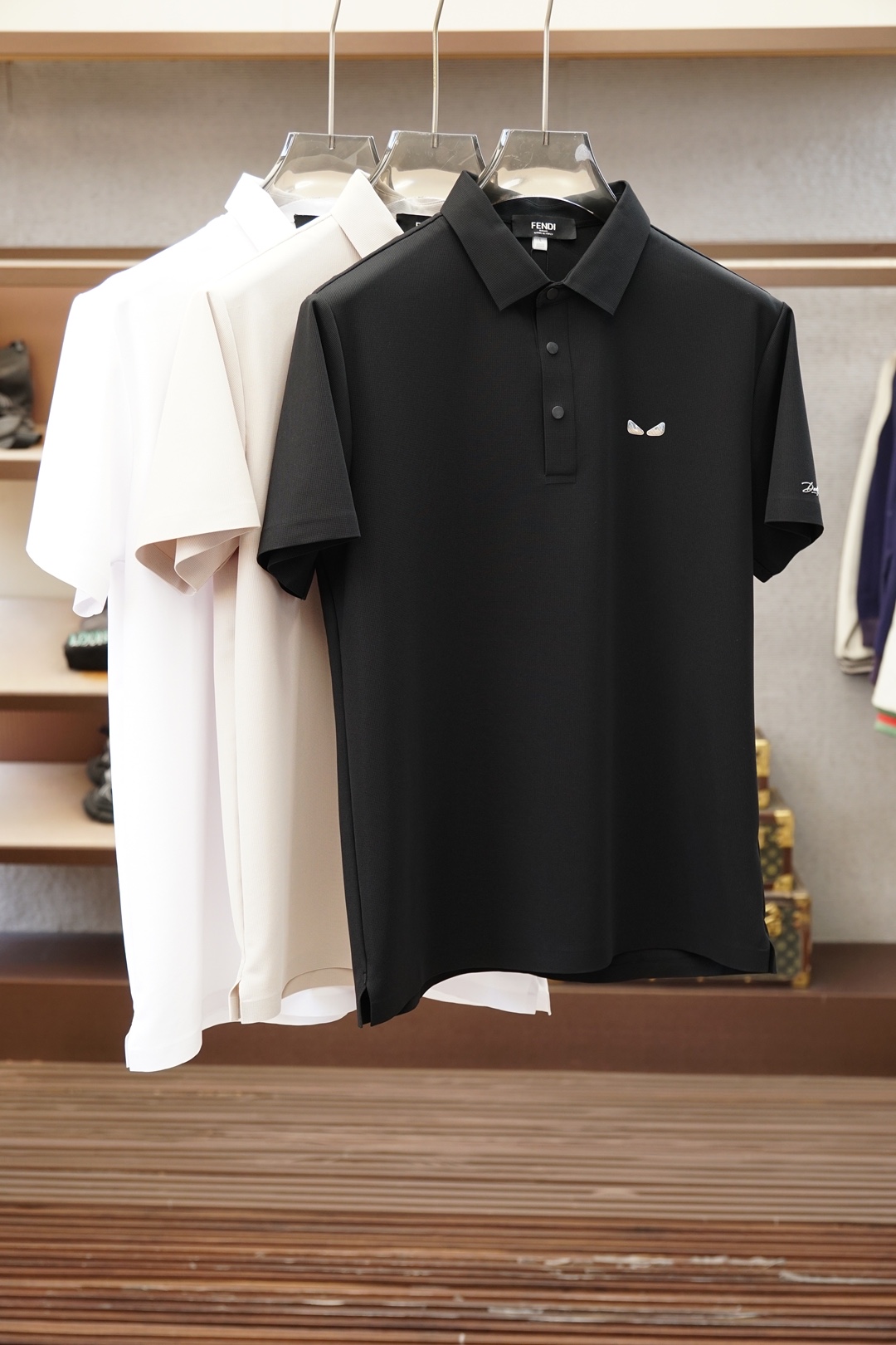 NO:935894,Fendi  The 2026 spring and summer new men's short-sleeved shirt outlines the classic silhouette with clean and simple lines, and the solid color main tone reveals exquisite details in a low-key manner. The short-sleeved design fits the body shape, taking into account both practicality and elegance. The small embroidered logo on the left chest shows the brand identity in a low-key manner, unobtrusive but with its own style. Fabric  Made of elastic ice silk, it feels soft and skin-friendly, breathable and sweat-absorbent, adapts to the changeable climate of spring and summer, and is suitable for daily commuting or leisure occasions. The original Italian craftsmanship reflects the spirit of ingenuity from weaving to tailoring. The version is crisp and stylish, and it is not easy to deform after long-term wear. The overall style combines business casual and urban luxury.  It is suitable for pairing with trousers to create an elite image in the workplace, or with denim shorts for a casual weekend style. Simple but not simple, classic with new ideas, it is a must-have item for modern men's wardrobe who pursue texture and taste. The attention to detail, such as the details on the collar and cuffs, make the entire dress stand out.  It feels more layered and high-end. Wearing it is not only the pursuit of comfortable life, but also the interpretation of exquisite lifestyle. Color: black, white, M-3XL (model weighs 173,143 pounds, upper body size L), fendi, shorts, T-shirt,19860909芬迪 2026春夏新品男士短袖衬衣,以利落简约线条勾勒经典轮廓,纯色主调低调中流露精致细节.短袖设计贴合身形,兼顾实用与优雅.左胸处小巧刺绣Logo,低调彰显品牌身份,不张扬却自有格调.面料选用弹力冰丝,触感柔软亲肤,透气吸汗,适应春夏多变气候,日常通勤或休闲场合皆宜.意大利原厂工艺,从织造到剪裁均体现匠心精神,版型挺括有型,久穿不易变形.整体风格融合商务休闲与都市轻奢,既适合搭配西裤打造职场精英形象,也可配牛仔短裤演绎周末随性风尚.简约而不简单,经典中见新意,是追求质感与品味的现代男士衣橱必备单品.细节处的用心,如领口与袖口的细节点缀,让整件衣服在视觉上更具层次感与高级感.穿上它,不仅是对舒适生活的追求,更是对精致生活方式的诠释.颜色黑色,白色,M-3XL（模特173,143斤上身L码）,,fendi,shorts,T-shirt,,Men's clothing