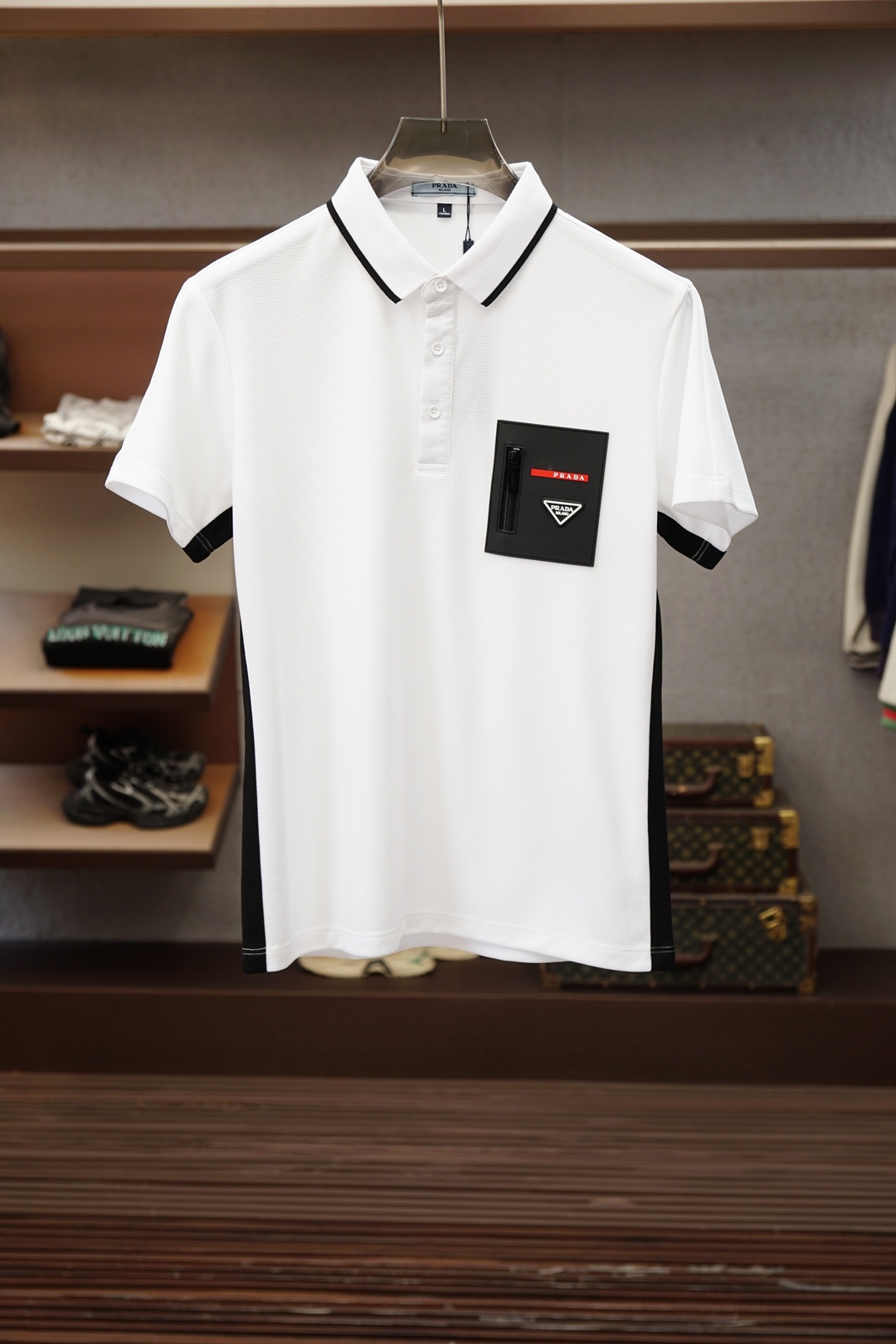 NO:935896,Prada  The 2026 spring and summer new men's short-sleeved shirt outlines the classic silhouette with clean and simple lines, and the solid color main tone reveals exquisite details in a low-key manner. The short-sleeved design fits the body shape, taking into account both practicality and elegance. The small embroidered logo on the left chest shows the brand identity in a low-key manner, without being ostentatious but with its own style.  The material is made of elastic ice silk, which is soft and skin-friendly, breathable and sweat-absorbent, adaptable to the changeable climate of spring and summer, and suitable for daily commuting or leisure occasions. The original Italian craftsmanship reflects the spirit of ingenuity from weaving to tailoring. The version is crisp and stylish, and will not be easily deformed after long-term wear. The overall style combines business casual and urban lightness.  Luxurious, it is suitable for pairing with trousers to create an elite image in the workplace, or with denim shorts for a casual weekend style. Simple but not simple, classic with new ideas, it is a must-have item in the wardrobe of modern men who pursue texture and taste. The attention to detail, such as the details on the collar and cuffs, makes the whole dress  The clothes are visually more layered and high-end. Wearing them is not only the pursuit of a comfortable life, but also the interpretation of an exquisite lifestyle. The color is black, M-4XL (model weighs 173,143 pounds, upper body size L), prada, shorts, T-shirt,19860909普拉达 2026春夏新品男士短袖衬衣,以利落简约线条勾勒经典轮廓,纯色主调低调中流露精致细节.短袖设计贴合身形,兼顾实用与优雅.左胸处小巧刺绣Logo,低调彰显品牌身份,不张扬却自有格调.面料选用弹力冰丝,触感柔软亲肤,透气吸汗,适应春夏多变气候,日常通勤或休闲场合皆宜.意大利原厂工艺,从织造到剪裁均体现匠心精神,版型挺括有型,久穿不易变形.整体风格融合商务休闲与都市轻奢,既适合搭配西裤打造职场精英形象,也可配牛仔短裤演绎周末随性风尚.简约而不简单,经典中见新意,是追求质感与品味的现代男士衣橱必备单品.细节处的用心,如领口与袖口的细节点缀,让整件衣服在视觉上更具层次感与高级感.穿上它,不仅是对舒适生活的追求,更是对精致生活方式的诠释.颜色黑,M-4XL（模特173,143斤上身L码）,,prada,shorts,T-shirt,,Men's clothing