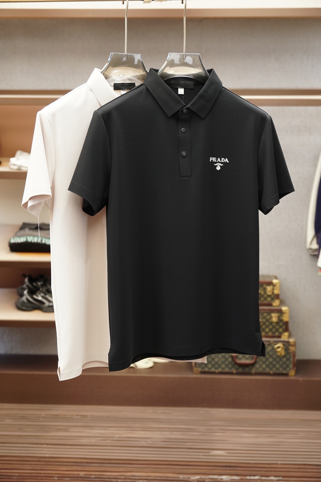 NO:935911,Prada  The 2026 spring and summer new men's short-sleeved shirt outlines the classic silhouette with clean and simple lines, and the solid color main tone reveals exquisite details in a low-key manner. The short-sleeved design fits the body shape, taking into account both practicality and elegance. The small embroidered logo on the left chest shows the brand identity in a low-key manner, without being ostentatious but with its own style.  The material is made of elastic ice silk, which is soft and skin-friendly, breathable and sweat-absorbent, adaptable to the changeable climate of spring and summer, and suitable for daily commuting or leisure occasions. The original Italian craftsmanship reflects the spirit of ingenuity from weaving to tailoring. The version is crisp and stylish, and will not be easily deformed after long-term wear. The overall style combines business casual and urban lightness.  Luxurious, it is suitable for pairing with trousers to create an elite image in the workplace, or with denim shorts for a casual weekend style. Simple but not simple, classic with new ideas, it is a must-have item in the wardrobe of modern men who pursue texture and taste. The attention to detail, such as the details on the collar and cuffs, makes the whole dress  The clothes are visually more layered and high-end. Wearing them is not only the pursuit of a comfortable life, but also the interpretation of an exquisite lifestyle. The color is black, M-4XL (model weighs 173,143 pounds, upper body size L), prada, shorts, T-shirt,19860909普拉达 2026春夏新品男士短袖衬衣,以利落简约线条勾勒经典轮廓,纯色主调低调中流露精致细节.短袖设计贴合身形,兼顾实用与优雅.左胸处小巧刺绣Logo,低调彰显品牌身份,不张扬却自有格调.面料选用弹力冰丝,触感柔软亲肤,透气吸汗,适应春夏多变气候,日常通勤或休闲场合皆宜.意大利原厂工艺,从织造到剪裁均体现匠心精神,版型挺括有型,久穿不易变形.整体风格融合商务休闲与都市轻奢,既适合搭配西裤打造职场精英形象,也可配牛仔短裤演绎周末随性风尚.简约而不简单,经典中见新意,是追求质感与品味的现代男士衣橱必备单品.细节处的用心,如领口与袖口的细节点缀,让整件衣服在视觉上更具层次感与高级感.穿上它,不仅是对舒适生活的追求,更是对精致生活方式的诠释.颜色黑,M-4XL（模特173,143斤上身L码）,,prada,shorts,T-shirt,,Men's clothing