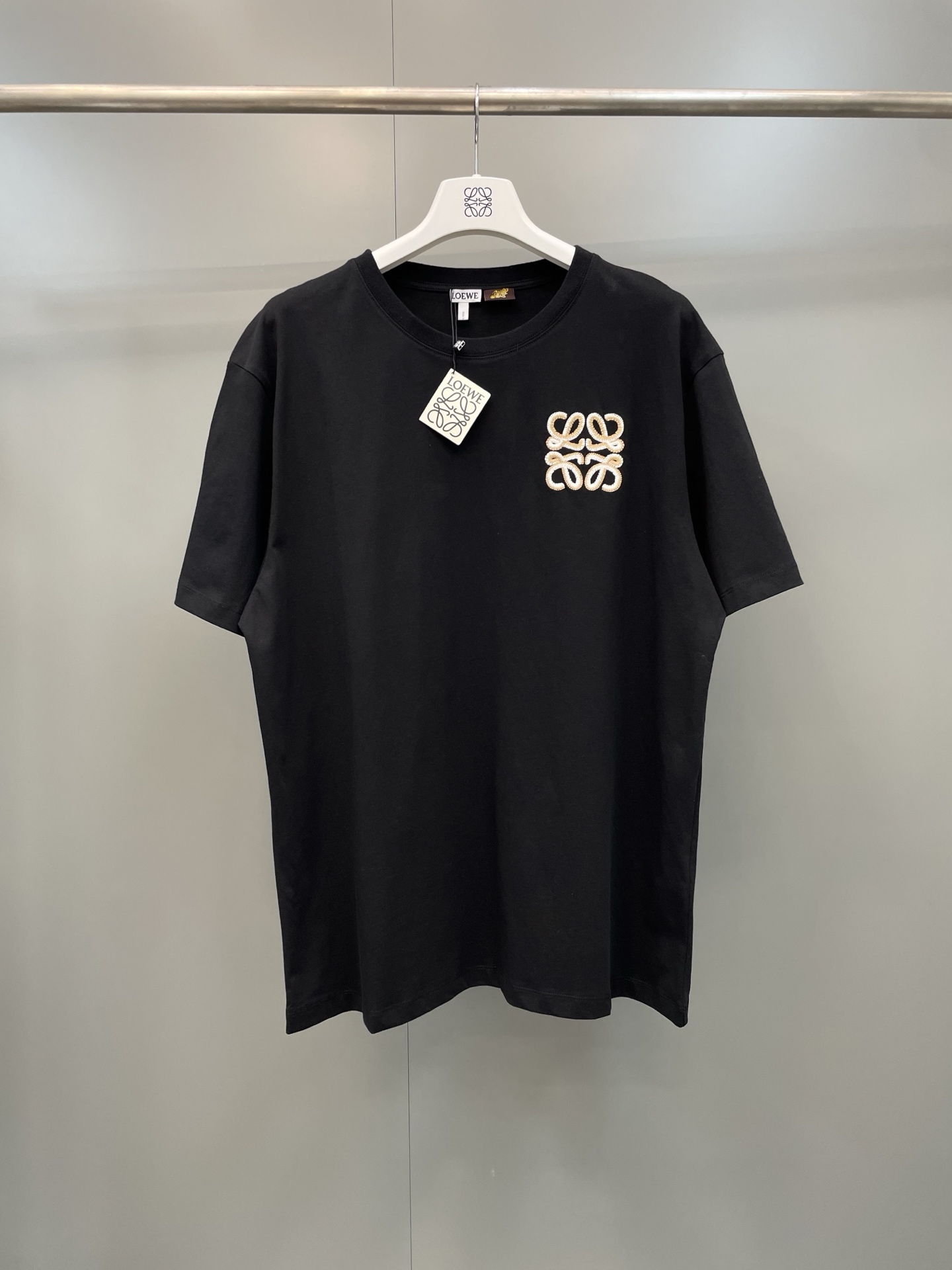 NO:822243,Loewe26ss new flat embroidered logo short-sleeved T-shirt, selection  Made of 24-count high-count combed cotton, the fabric has a weight of 185G. It has a delicate skin-friendly touch and an excellent crisp drape. The upper body is breathable and dry, and will not be easily deformed after being washed for a long time. The round neck is made of ribbed natural cloth. The collar is precision-locked and has excellent stretch resistance. It is not easy to loose and deform after repeated wear and washing. The iconic Anagram logo on the left side of the body is made with flat embroidery technology, using double-strand metal embroidery thread + white cotton thread to contrast colors.  Outline, high embroidery thread density, neat and full threading, no skipped stitches or raw edges on the edges of the pattern, both three-dimensional and recognizable. The ready-made garments are cut in an Oversized silhouette, with dropped shoulder sleeves designed to modify the shoulder line, and the hem is hemmed with double-needle flat stitching technology, and the overall threading is smooth and smooth., Loewe-clothing, loewe, loewe, versace, T-shirt, tees, t-shirt,19860909Loewe26ss新款平绣徽标短袖T恤,甄选 24支高支精梳棉打造,面料克重为185G,兼具细腻亲肤的触感与优良的挺括垂坠感,上身透气干爽,久洗不易变形；圆领处采用罗纹本布包边领,领口锁边工艺精密,抗拉伸性优异,反复穿洗不易松垮变形.衣身左侧标志性的Anagram徽标,采用平绣工艺打造,以双股金属绣线+本白棉线撞色勾勒,绣线密度高、走线工整饱满,图案边缘无跳针、毛边,立体感与辨识度兼具.成衣采用Oversized廓形剪裁,落肩袖设计修饰肩线,下摆采用双针平缝工艺锁边,整体走线平整顺滑.,罗意威-服装,loewe,loewe,versace,T-shirt,tees，t-shirt,,Women's clothing