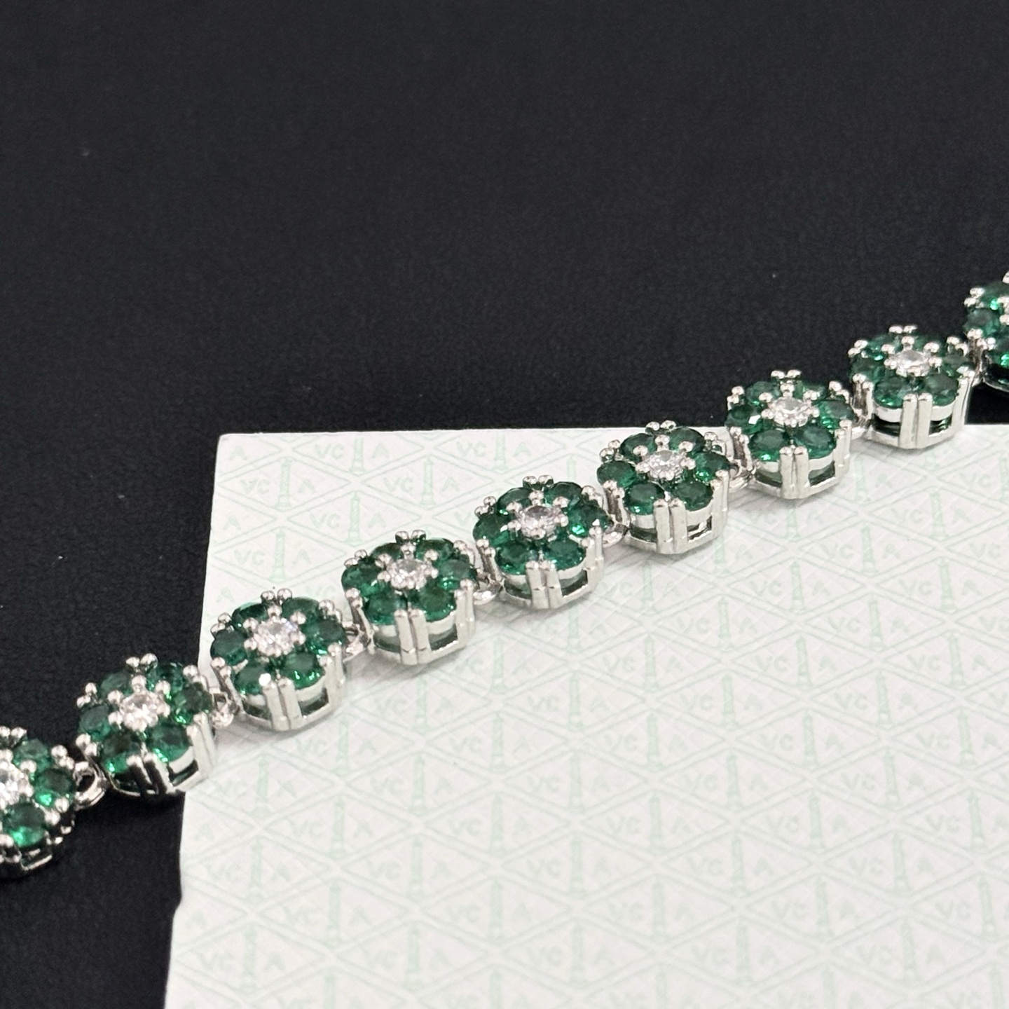 Bracciale Van Cleef Arpels Fleurette metallo oro bianco tonalità argento pietre preziose verde smeraldo diamanti bianchi trasparenti 18 cm