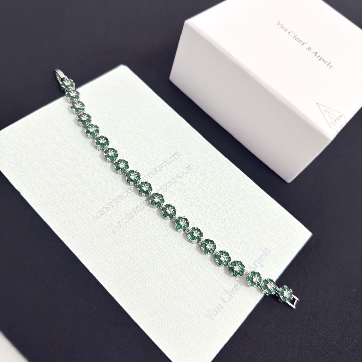 Bracciale Van Cleef Arpels Fleurette metallo oro bianco tonalità argento pietre preziose verde smeraldo diamanti bianchi trasparenti 18 cm