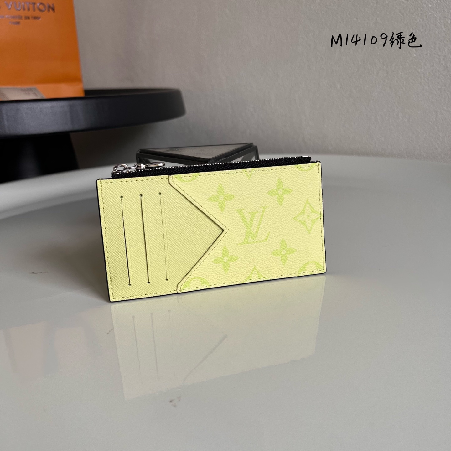  M14109绿色 這款零錢名片夾以Monogram塗層帆布製造，搭配色調相襯的Taïga牛皮，配以黃色