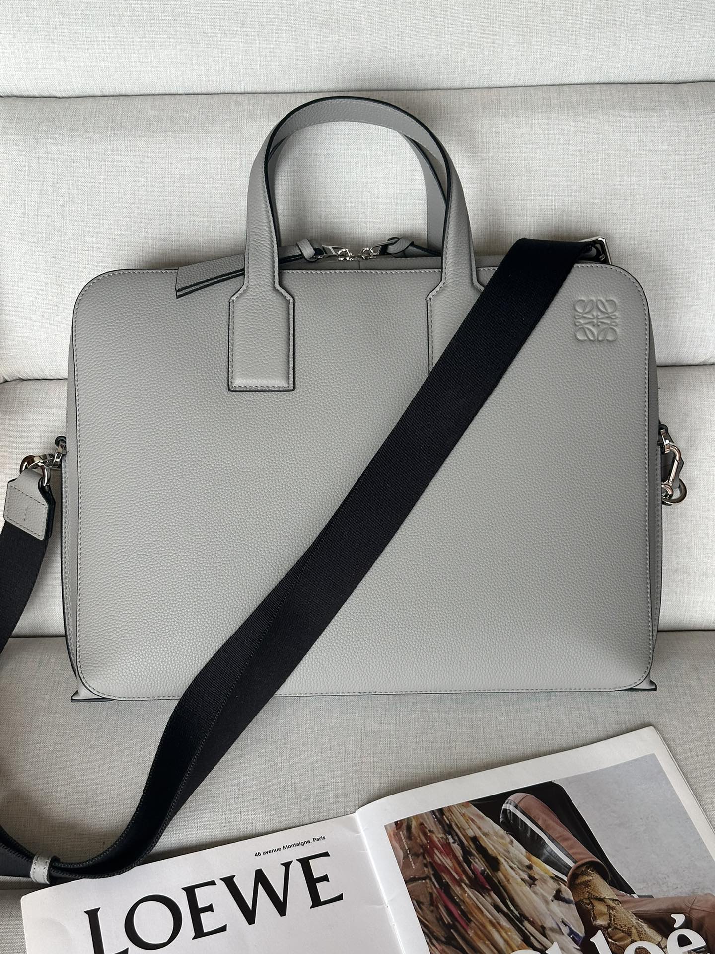 NO:185141,Genuine grade original leather version Lychee leather grey Size 27.5-7.5-38 Model 3066 This briefcase is slim and compact in shape and is just right in size. It is suitable for storing documents and daily belongings, ensuring orderly, with abundant internal capacity and multiple compartments. It is neatly designed, with a soft and crisp silhouette. It is made of sturdy and wear-resistant soft grain calf leather. It can be held by the handle or a removable and adjustable webbing shoulder strap to ensure a comfortable feeling during commuting. Main features T-shaped metal accessories, double-head zippered bags with calf leather zipper heads in the same color, herringbone pattern cotton canvas lining, a zipper pocket, a flat compartment with car wire insert bags, black handmade oil edges, and Anagram pattern embossed in the same color., Superior Loewe, loewe, cowhide19860909正品级 原厂皮版本 荔枝皮 灰色 尺寸27.5-7.5-38 型號3066 这款公文包造型纤薄小巧,尺寸恰到好处,适合收纳文件和日常随身物品,确保井井有条,内部容量充裕,设有多个隔层.设计利落,廓形柔和而又不失挺括,选用坚固耐磨的柔软粒面小牛皮制成.既可拎住手柄,亦可使用可拆可调节的织带肩带背携,确保通勤途中倍感舒适.主要特点T形金属配饰,双头拉链包口搭配同色系小牛皮拉链头,人字纹图案棉质帆布衬里,一个拉链口袋,一个平隔层配有车线插袋,黑色手工油边,同色系Anagram图案压花.,特级罗意威,loewe,cowhide,Bag