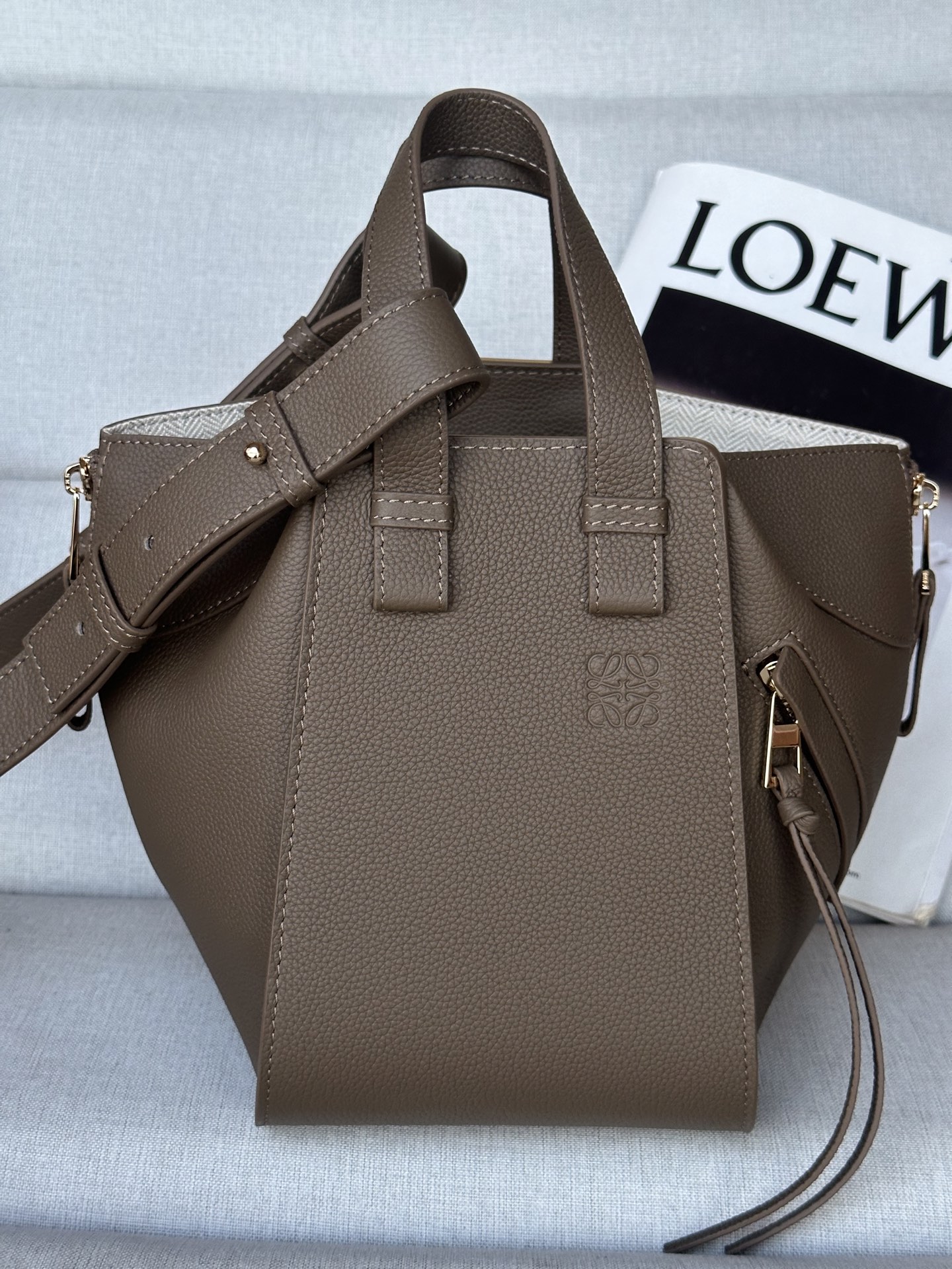 NO:341241,Extra loewe hammock compact version. Taupe between mini and small Model 8047 compaet version New size 20-19-14 Hammock is a multi-purpose handbag with soft side bread that releases the sides to change shape. Loop straps allow for a variety of ways to wear the handbags. This new compact version is made of soft grain cowhide leather Crossbody, shoulder or carried through top handle Removable, adjustable shoulder straps Internal hook closure Two internal insert pockets, one external zipper pocket Customizable with shoulder straps and personalized hanging Herringbone cotton canvas lining Anagram embossed, super Loewe, loewe, cowhide19860909特级 loewe hammock紧凑版本. 灰褐色 介于mini跟小号中间 型号8047 compaet珍版本 新尺寸20-19-14 Hammock 是一款带有柔软侧面包身的多功能手袋,可释放侧面来改变形状. 环状带子可以使手袋有多种佩戴方式. 这个全新的紧凑版本采用柔软粒面牛皮革制成 斜挎,肩背或通过顶部提手携带 可拆卸,可调节肩带 内部钩扣封口 两个内部插袋,一个外部拉链口袋 可以使用肩带和个性化挂饰进行定制 人字纹棉帆布衬里 Anagram 压纹,特级罗意威,loewe,loewe,cowhide,Bag