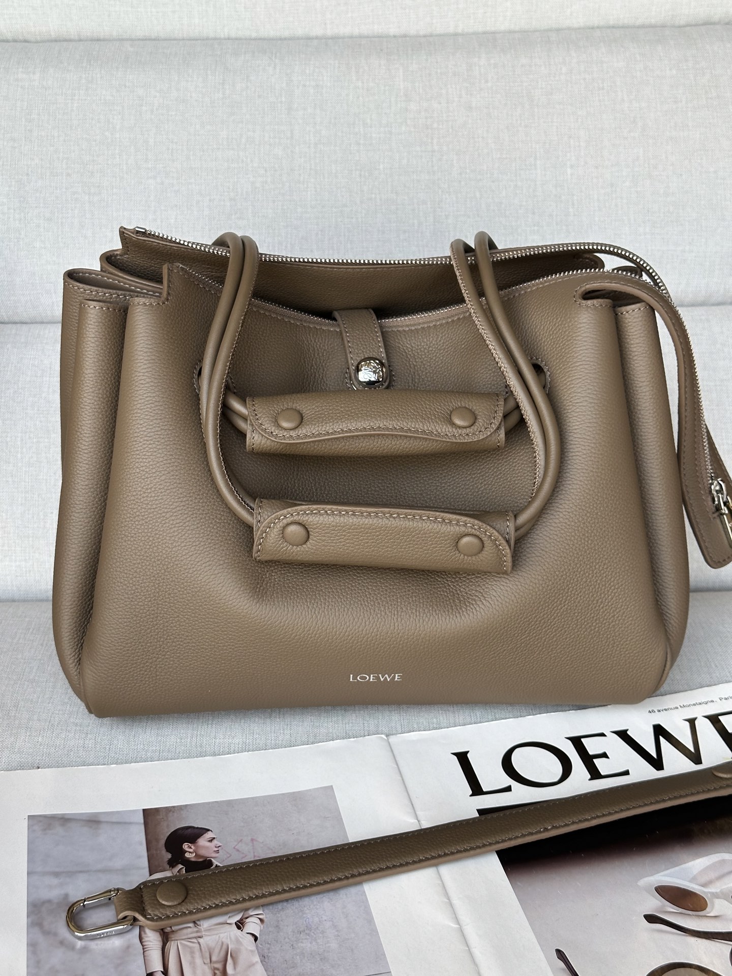 NO:339898,Super Madrid Size: 28.5*11*23cm Gray Color Medium Soft Cowhide Madrid Handbag Madrid has a soft structure trapezoidal shape, with a gusset design, with adjustable handles and Pebble magnetic buckles. This medium version is made of soft cowhide leather. It can be shoulder-mounted, cross-body or hand-mounted Adjustable shoulder straps, with leather extension straps Anagram Pebble magnetic buckle closure, zipper closure Anagram Pebble Metal foot nails Napa sheepskin lining, super Loewe, cowhide, sheepskin19860909特级 马德里 尺寸:28.5*11*23cm  灰谒色 中号柔软牛皮革 Madrid 手袋 Madrid 具有柔软的结构感梯形造型,采用角撑设计,搭配可调节提手和 Pebble 磁扣.此中号版本采用柔软牛皮革制成. 可肩背、斜挎或手提 可调节肩带,搭配皮革延长带 Anagram Pebble 磁扣开合,拉链开合 一个拉链内袋,一个内部卡位 Anagram Pebble 金属脚钉 纳帕羊皮革衬里,特级罗意威,loewe,cowhide,sheepskin,Bag