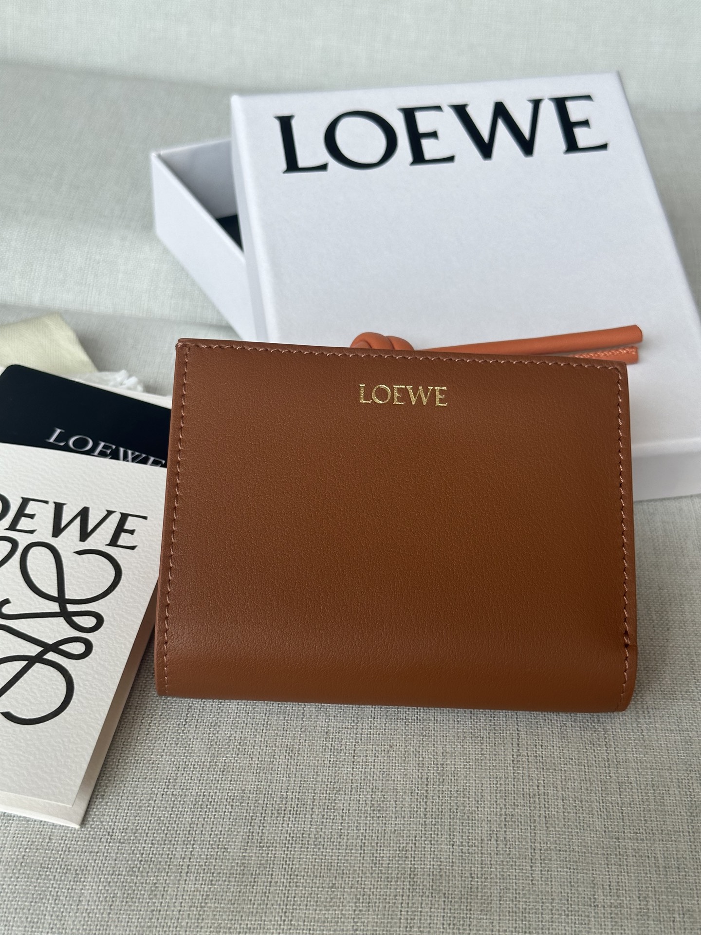 NO:574120,Premium ready stock glossy nappa calfskin short leather wallet with knotted zippers. Model 11.5-8.5, super Loewe, loewe, loewe, cowhide19860909特级 现货 亮面納帕小牛皮繩結短皮夾 型號X1 胡桃色 亮面納帕小牛皮短皮夾,對比色繩結拉鍊頭. 六個置卡夾,三個內部插袋 一個拉鍊硬幣隔層,小牛皮拉鍊頭 按扣 對比色小牛皮內裡 LOEWE 燙金 公分·in 顏色 棕褐色/木瓜色 金屬色 金色 材質 亮面納帕小牛皮 11.5-8.5,特级罗意威,loewe,loewe,cowhide,Bag