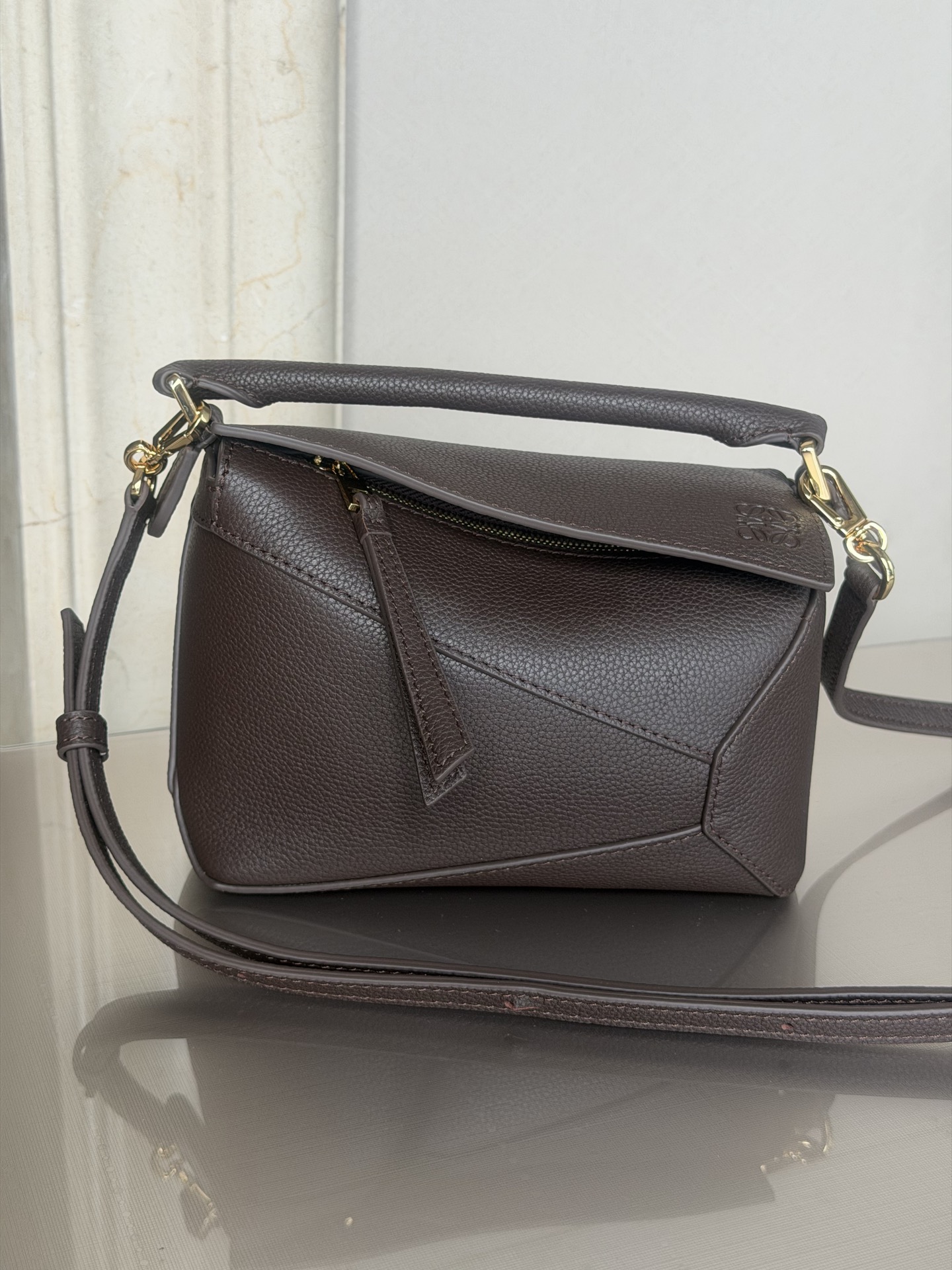 NO:617924,Premium Puzzle Edge Dark Brown Handbag Latest version with adjustable shoulder straps Debut handbag from Lo*we* The rectangular shape and precise cutting techniques create the unique geometric lines of the Puzzle* This mini version is crafted from satin calf leather with cage-stitched edges  The Mini Puzzle can hold, for example, a small vertical wallet, most cell phone sizes (up to 6.1 inches) and sunglasses cases, and can be worn over the shoulder or across the body*Adjustable shoulder strap, removable*Zip closure,*Cow leather zipper pull*Herringbone cotton canvas lining Anagram embossed size: 18*12.5*8CM19860909特级 Puzzle Edge 深咖啡色 手袋 最新版本肩带可调节 Lo*we推出的首次亮相手提包*长方体形状和精确的切割技术创造了 Puzzle 独特的几何线条*这个迷你版本采用缎面牛皮革制成,带有笼盖缝线边缘 迷你Puzzle可以容纳例如一只小号垂直钱包、大多数尺寸的手机（最大6.1英寸）和太阳镜盒,肩背或斜挎*肩带可调节,可拆卸*拉链封口,*牛皮革拉链头*人字纹棉质帆布衬里Anagram 压纹 size:18*12.5*8CＭ 型号3000m,特级罗意威,loewe,wallets,cowhide,Bag