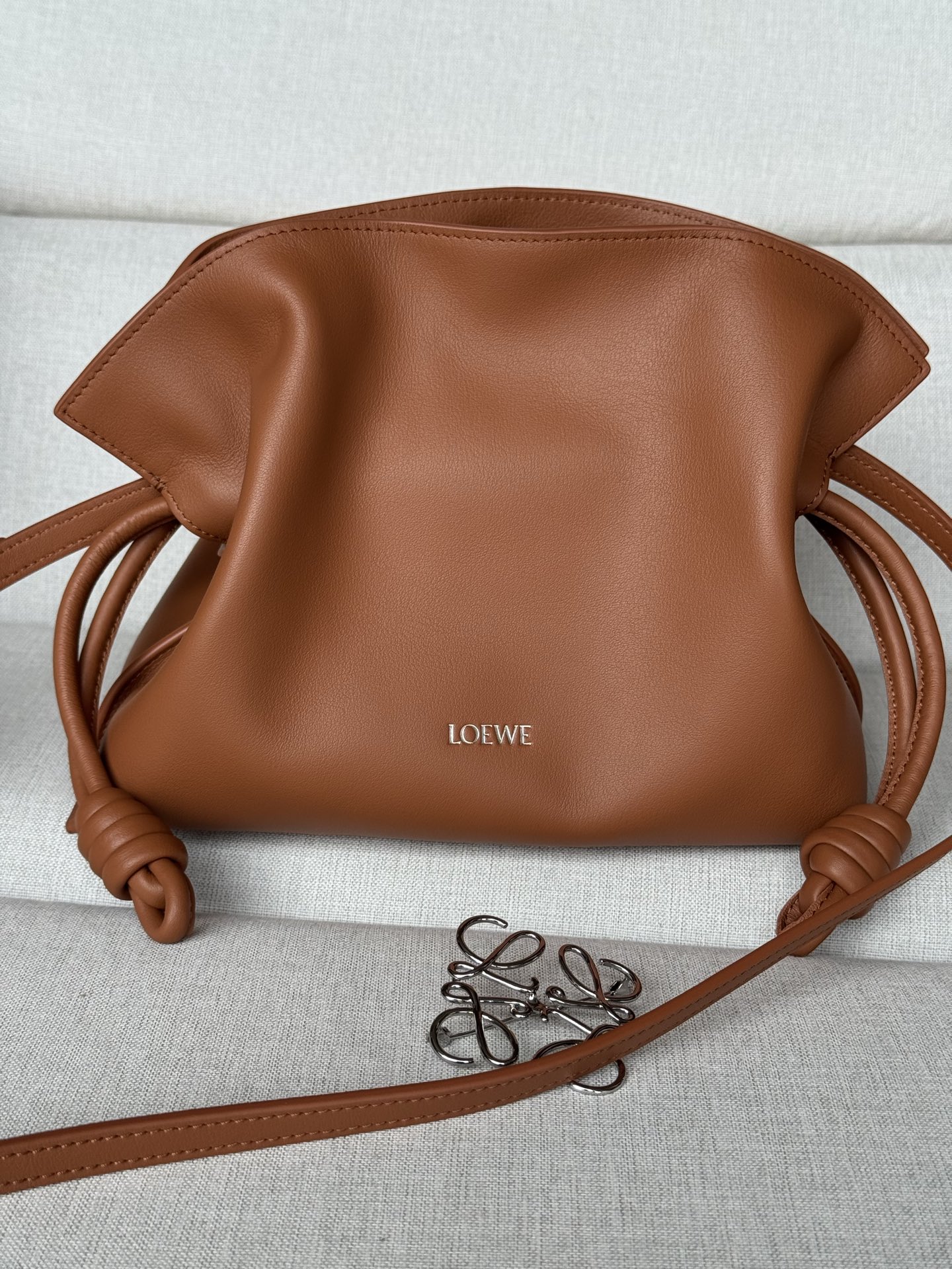 NO:583776,Premium squirrel brown bag comes with long shoulder strap Mini Nappa cow leather Flamenco clutch Model 11050S 23.9-9-18cm The Flamenco clutch released in the 1870s, fastened with a drawstring and tied with the iconic coiled knot. This mini version is made of Nappa cow leather. Can be worn on the shoulder, cross-body or handheld Detachable and adjustable shoulder strap Low profile magnetic buckle closure  Gold suede lining LOEWE hot stamping or silver, premium Loewe, loewe, loewe, handbag, cowhide19860909特级 松鼠棕 包包自配长肩带 迷你纳帕牛皮革 Flamenco 手拿包 型号11050S 23.9-9-18cm 十九世纪七十年代发布的 Flamenco 手拿包,采用拉绳收紧,并打上标志性的盘绕结.此迷你版本采用纳帕牛皮革制成. 可肩背、斜挎或手提 可拆卸可调整肩带 低调的磁扣开合 金色绒面革衬里 LOEWE 烫金或烫银,特级罗意威,loewe,loewe,handbag,cowhide,Bag