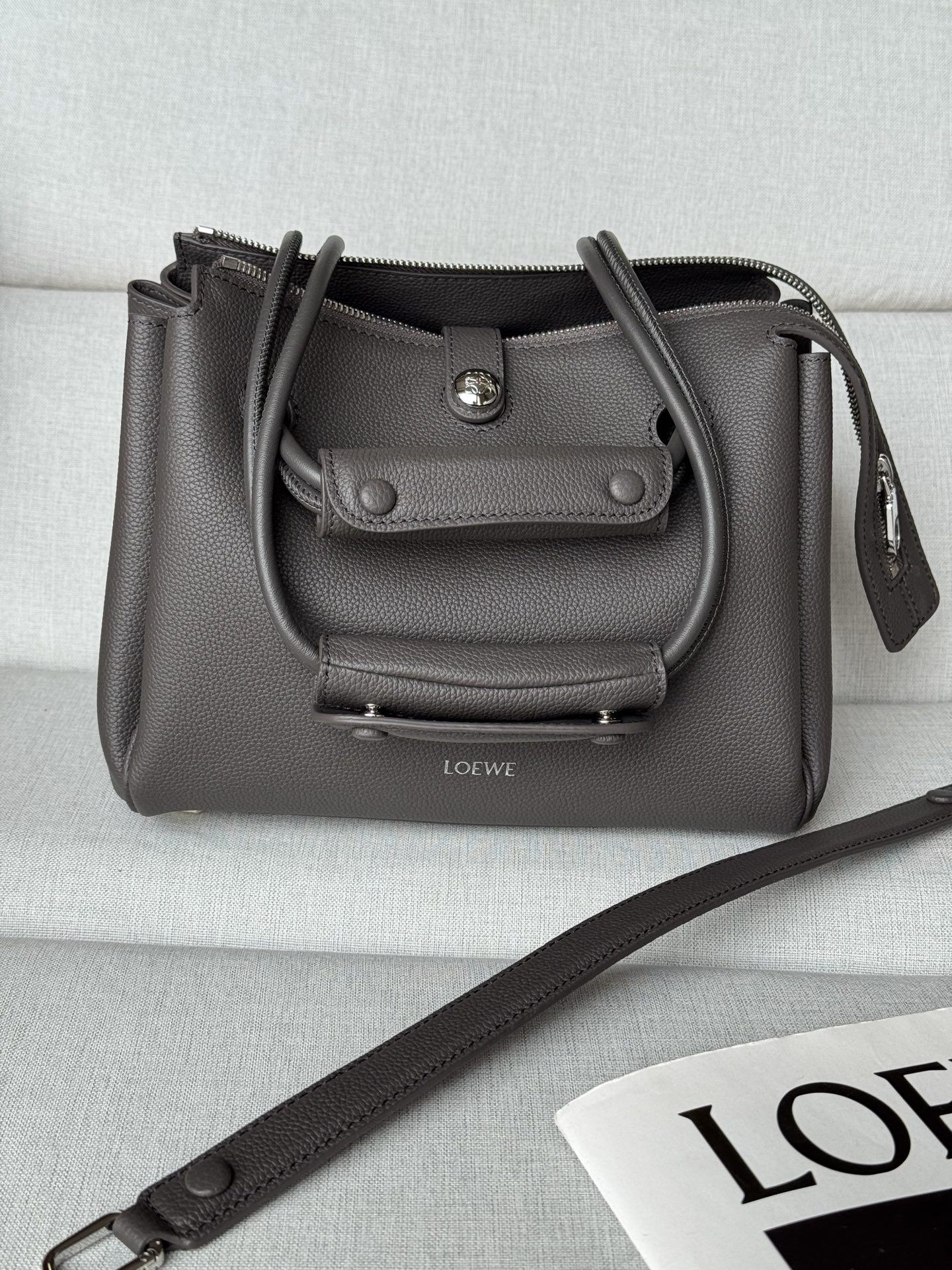 NO:617875,Premium Small*0256 Jet Black Size: 23.5*10*19cm Madrid Featuring a soft structured trapezoidal shape, gusseted design, adjustable handles and Pebble magnetic closure. This small version is made of soft calfskin. Can be worn on the shoulder, crossbody or by hand Adjustable shoulder strap with leather extension Anagram Pebble magnetic closure, zipper closure One zippered inner pocket Anagram Pebble metal feet  Nappa sheep leather lining, premium Loewe, loewe, cowhide, sheepskin19860909特级 小号*0256 乌黑色 尺寸:23.5*10*19cm Madrid 具有柔软的结构感梯形造型,采用角撑设计,搭配可调节提手和 Pebble 磁扣.此小号版本采用柔软牛皮革制成. 可肩背、斜挎或手提 可调节肩带,搭配皮革延长带 Anagram Pebble 磁扣开合,拉链开合 一个拉链内袋 Anagram Pebble 金属脚钉 纳帕羊皮革衬里,特级罗意威,loewe,cowhide,sheepskin,Bag
