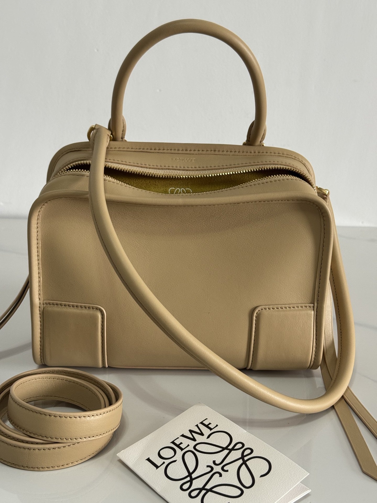 NO:852289,EXTRA SMALL Amazona Bag in Soft Calfskin Model Beige The Amazona reinterprets the legendary LOEWE bag in a relaxed silhouette with a single top handle. The bag has an open design and the main compartment is secured with a hidden buckle. Comes with a detachable shoulder and crossbody strap for a practical style. This small version is made of soft calfskin. Three ways to carry short handles, detachable shoulder and crossbody straps Zipper with two leather zipper pulls  Two compartments, main compartment with magnetic closure Internal flat pocket Customizable D-ring on left side Suede lining LOEWE hot stamping or silver, Double L embossed branding in Metallic color Palladium Main material Soft calf leather Strap length 108 cm Handle drop 11 cm Weight 0.66 kg Height 18.5 cm Width  24.5 cm Depth 10 cm, premium Loewe, loewe, loewe, cowhide19860909特级 小号柔软牛皮革 Amazona 手袋 型号 米色 Amazona 重新诠释 LOEWE 传奇手袋,呈现休闲轮廓,搭配单一顶部提手.手袋采用开放式设计,主隔层以隐藏式扣固定.搭配可拆卸肩背和斜挎背带,打造实用风格.此小号版本采用柔软牛皮革制成. 三种携带方式短提手、可拆卸肩背和斜挎背带 拉链配有两个皮革拉链头 两个隔层,主隔层以磁扣开合 内部扁平口袋 左侧 D 形环可定制 绒面革衬里 LOEWE 烫金或烫银,Double L 压纹品牌标志 公分·in Metallic colour 钯金色 Main material 柔软牛皮革 Strap length 108 cm 肩带长度 27 / 50 cm Handle drop 11 cm Weight 0.66 kg Height 18.5 公分 Width 24.5 公分 Depth 10 公分,特级罗意威,loewe,loewe,cowhide,Bag