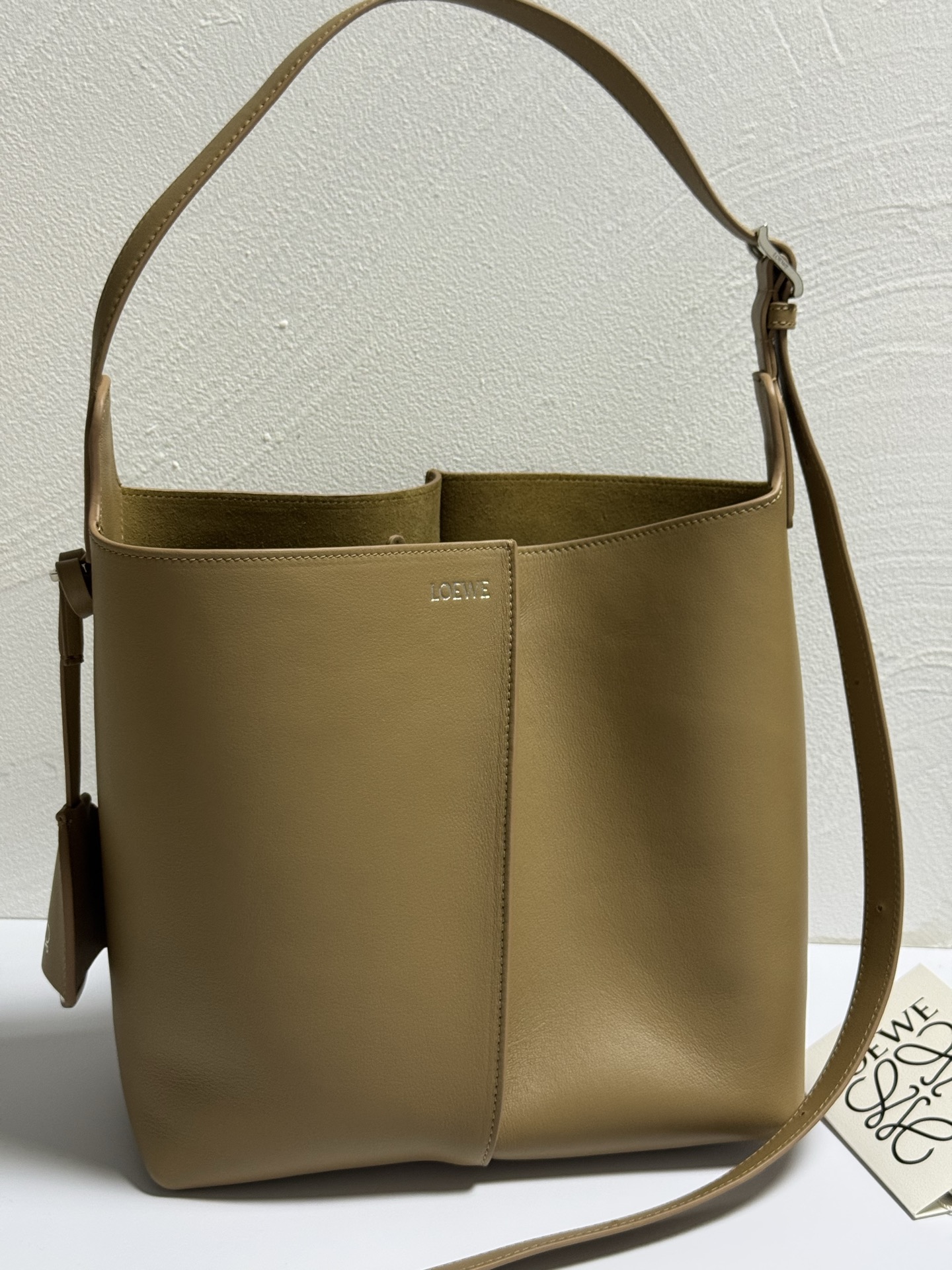 NO:852301,Premium Loewe Mocha Medium Smooth Cow Leather Bilbao Bucket Bag Color Model 11776 Bilbao trapezoidal bucket bag, presenting a simple geometric design. Made of leather splicing, with pleats in the center, soft and close-fitting shape, ideal for daily carry. This medium version is made of smooth cow leather. Can be worn on the shoulder or crossbody. Adjustable shoulder strap. Detachable Double  L-embossed leather bell-shaped charm with built-in practical bottle opener. Extra external D-ring for personalized charms. Hook fastener to secure belongings. Suede lining. LOEWE hot silver 25-24-13, premium Loewe, loewe, loewe, cowhide19860909特级 loewe摩卡 中号光滑牛皮革 Bilbao 水桶手袋 颜色 型号11776 Bilbao梯形水桶手袋,呈现简约几何设计.采用皮革拼接打造,中央饰有褶裥,造型柔软贴身,是日常随身携带的理想选择.此中号版本采用光滑牛皮革制成. .可肩背或斜挎 .可调节肩带 .可拆卸 Double L压纹皮革钟形挂饰,内藏实用开瓶器.额外的外部D形环,可用于搭配个性化挂饰.钩扣可固定随身物品 .绒面革衬里 .LOEWE烫银 25-24-13,特级罗意威,loewe,loewe,cowhide,Bag