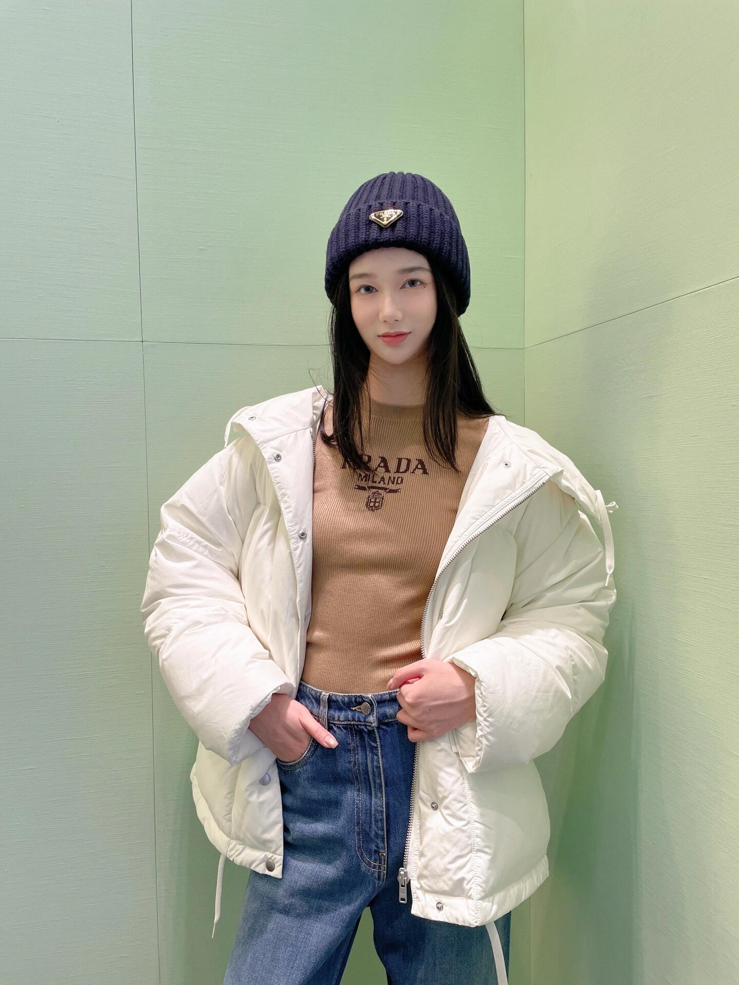 💰批690 🆕Prad* 25Fw秋冬新款 三角徽标白色连帽夹克羽绒服丨⚠独家yb开发！高版出品！采用品牌标志性的 Re-Nylon 再生尼龙面料（由海洋回收塑料净化再生而成），兼具防水功能性与柔和哑光质感，米白色调在秋冬衣橱中更显干净高级；70%鹅绒填充饱满蓬松，连帽带抽绳可调节松紧，下摆抽绳自由控制廓形；双侧大贴袋兼具工装实用性与视觉层次感，日常出行随手置物便利又时髦。现货发售S/M/L