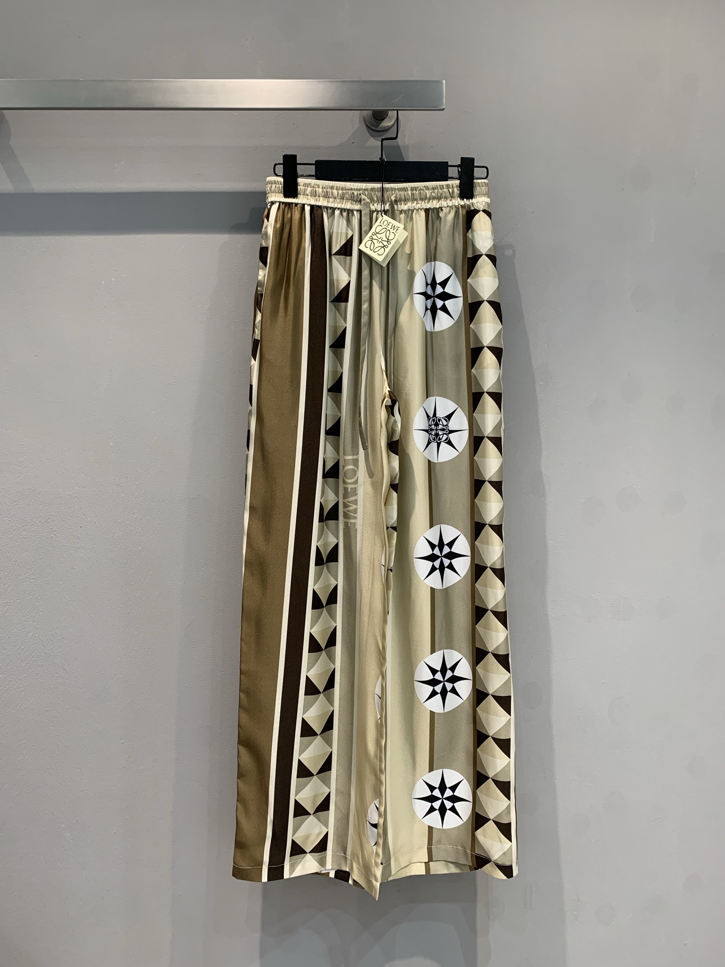 NO:410950,New model is shipped. Original development. Loew*2025 spring and summer new geometric graphic contrasting silk wide-leg pants. Classic khaki tones, paired with personalized geometric patterns and unique star elements, full of artistic and design. Mulberry silk fabric. The texture is delicate and smooth, scattered, creating a chic and atmospheric style, modifying the body and showing casualness. The elastic waist design brings a comfortable wearing experience. Whether it is paired with a simple white T to create a casual style or a delicate top to attend a fashionable occasion, you can easily grasp it, helping you take confident steps and become a fashionable ICON for walking on the street. Number 36 38 40,,loewe, real silk,alexander wang19860909新款出货啦 原版开发 Loew*2025春夏新款几何图形撞色真丝阔腿裤.经典卡其色调,搭配个性几何图案与独特星芒元素,艺术感与设计感拉满.桑蚕丝面料.质感细腻流畅垂坠,塑造潇洒大气的版型,修饰身形又尽显随性.松紧腰设计带来舒适穿着体验,无论是搭配简约白T打造休闲风,还是配上精致上衣出席时尚场合,都能轻松拿捏,助你踏出自信步伐,成为街头行走的时尚ICON.码数36 38 40,,loewe,real silk,alexander wang,Women's clothing