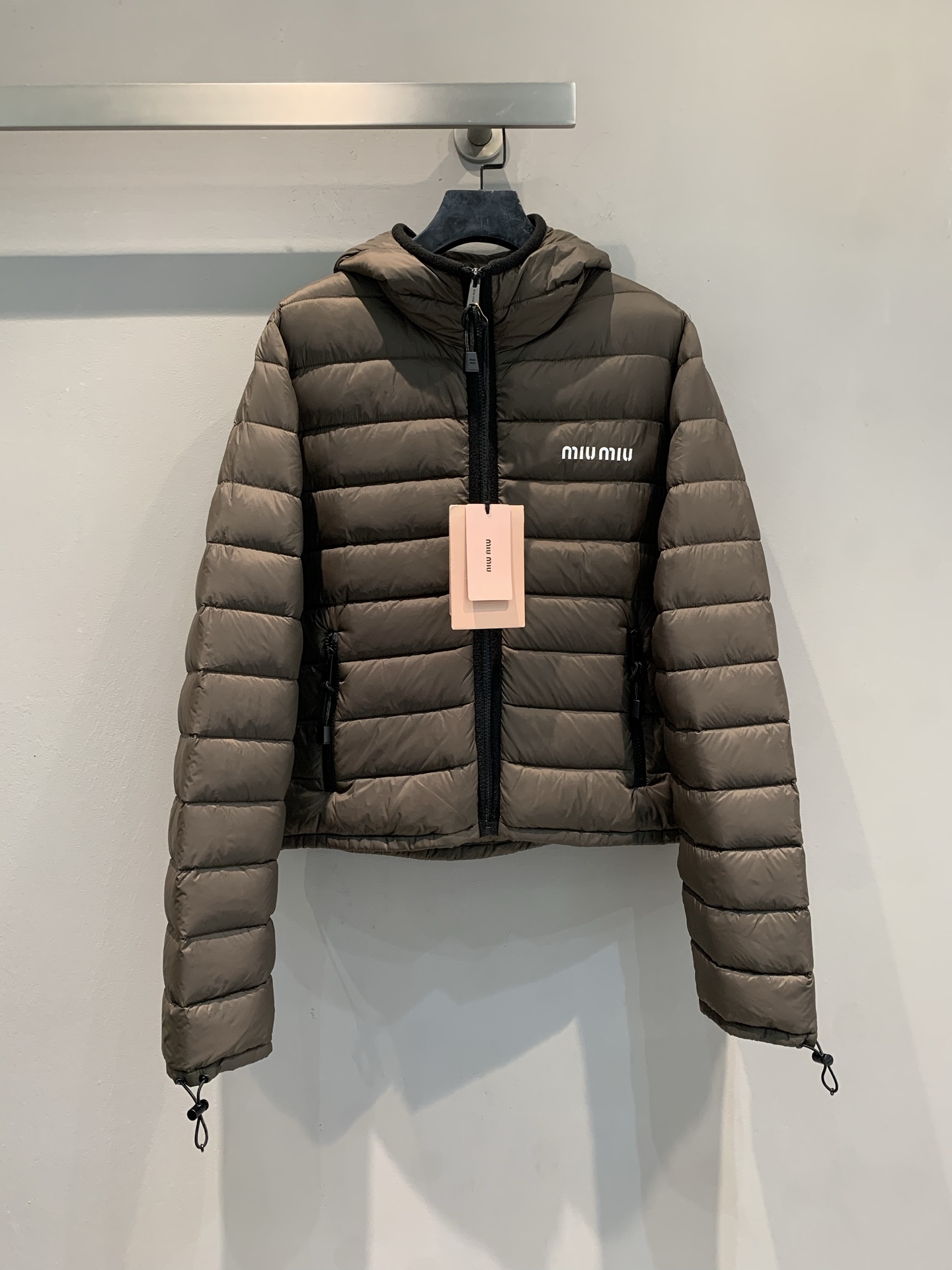 NO:544306,New models with dust bags are shipped. Real shot of large-scale products. Miumi* new fashionable and versatile drawstring lightweight short down jacket. Olive brown lightweight white goose velvet fills, light but firmly locks the temperature, bid farewell to the heavy burden of winter; the hooded design is matched with black contrasting zippers, and the sweet and cool feeling is coming out; the white letter logo on the chest is eye-catching, the short silhouette raises the body proportions, and the details of the drawstring at the cuffs are tricky, so that the light down can also be worn with a full sense of shape. SML, miumiu, down jacket, hats, alexander wang19860909配防尘袋新款出货啦 大货实拍 Miumi*秋冬新款时髦百搭抽绳轻量短款羽绒服.橄榄棕轻量白鹅绒填充,轻薄却牢牢锁温,告别冬日厚重负担；连帽设计搭配黑色撞色拉链,甜酷感呼之欲出；胸前白色字母标识醒目吸睛,短款廓形拉高身材比例,袖口抽绳细节暗藏小心机,让轻羽绒也能穿出满满造型感.码数SML,,miumiu,down jacket,hats,alexander wang,Women's clothing