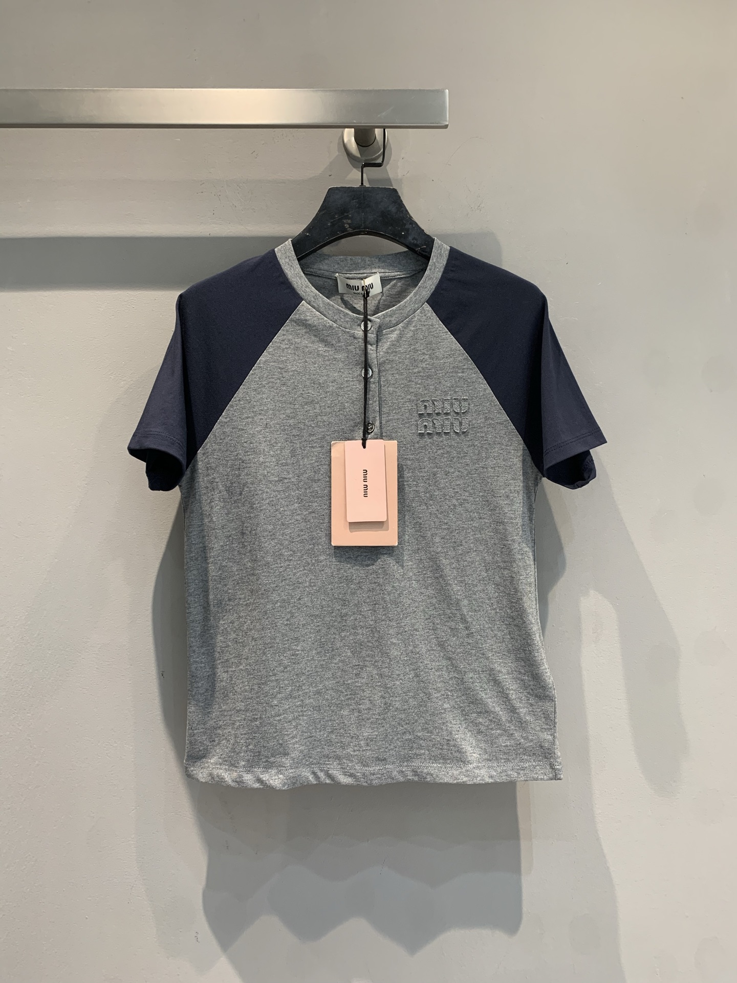 NO:734241,The new model is shipping. The original development Miumi*2026 spring and summer new half open collar contrasting color raglan sleeve T-shirt. The gray and blue splicing design is super college style, retro and age-reducing!  The cotton blended fabric is soft and breathable, making it super comfortable to wear in summer. The three-dimensional appliqué logo on the chest is low-key and textured, and the details are perfect. It is a regular length and can be easily worn for commuting and leisure. It is versatile with jeans or shorts. It is a must-have and practical item in the wardrobe!  Code number SML,,miumiu,shorts,jeans,tees,t-shirt,19860909新款出货啦原版开发 Miumi*2026春夏新款半开领撞色插肩袖T恤,灰蓝拼接设计超有学院风,复古又减龄！棉混纺面料柔软透气,夏天穿超舒服.胸前立体贴布绣Logo低调有质感,细节满分.常规衣长,通勤休闲都能轻松驾驭,搭牛仔裤或短裤都很百搭,是衣橱必备实用单品！码数SML,,miumiu,shorts,jeans,tees，t-shirt,,Women's clothing