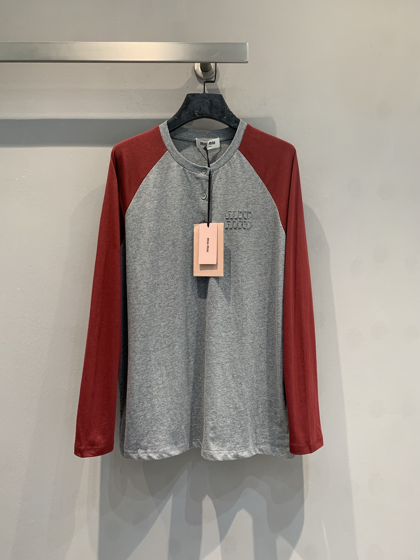 NO:736146,The new model is shipping. M original development Miumi*2026 early spring new style college style fashionable retro color matching raglan long-sleeved T-shirt, gray + Angora red contrasting colors, full of retro college style!  The cotton blended fabric is soft, comfortable and crisp, and is super friendly for daily wear. The raglan sleeves are designed to modify the shoulder lines, and the three buttons on the neckline can be opened or fastened, making the shape changeable. The three-dimensional appliqué embroidered logo on the chest is highly recognizable and full of details. Pair it with a work skirt or jeans to easily switch between sweet and cool or casual styles. It is a popular item in spring!  Size SML,,miumiu,skirts,jeans,tees,t-shirt,19860909新款出货啦M原版开发 Miumi*2026早春新款学院风时髦复古拼色插肩长袖T恤,灰色+安哥拉红撞色,复古学院风满满！棉混纺面料柔软舒适又挺括,日常穿着超友好.插肩袖设计修饰肩部线条,领口三颗纽扣可敞开或扣紧,造型多变.胸前立体贴布绣Logo,辨识度高,细节感十足.搭配工装裙或牛仔裤,轻松切换甜酷or休闲风,是春季百搭热门单品！码数SML,,miumiu,skirts,jeans,tees，t-shirt,,Women's clothing