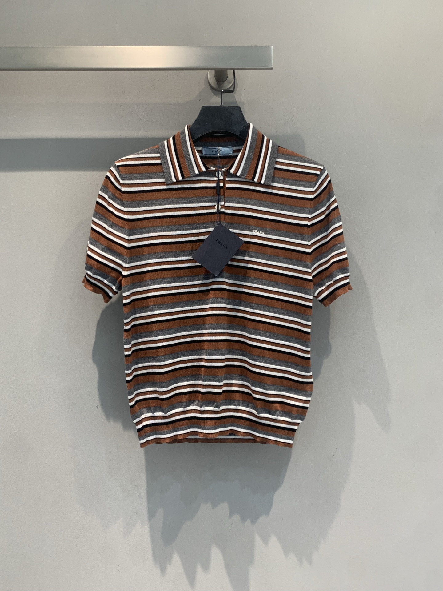 NO:869005,The new model has been shipped. The original development of Prad* new spring and summer fashionable retro striped knitted Polo shirt is made of soft knitted yarn, brown, gray and white striped design, retro and high-end. Classic lapel + contrasting color details, full of Italian campus style, short version to optimize body proportions, paired with high-waisted pants or wide-leg pants to show your temperament. It can be easily controlled for daily commuting and leisure, low-key and textured, it is a must-have item for 'old money style'!  Code number SML,,prada,19860909新款出货啦 原版开发 Prad*春夏新款时髦复古条纹针织Polo衫,采用柔软针织纱线,棕灰白条纹设计,复古又高级.经典翻领+撞色细节,意式校园风满满,短款版型优化身材比例,搭配高腰裤或阔腿裤超显气质.日常通勤、休闲都能轻松驾驭,低调又有质感,是“老钱风”穿搭必备单品！码数SML,,prada,,Women's clothing