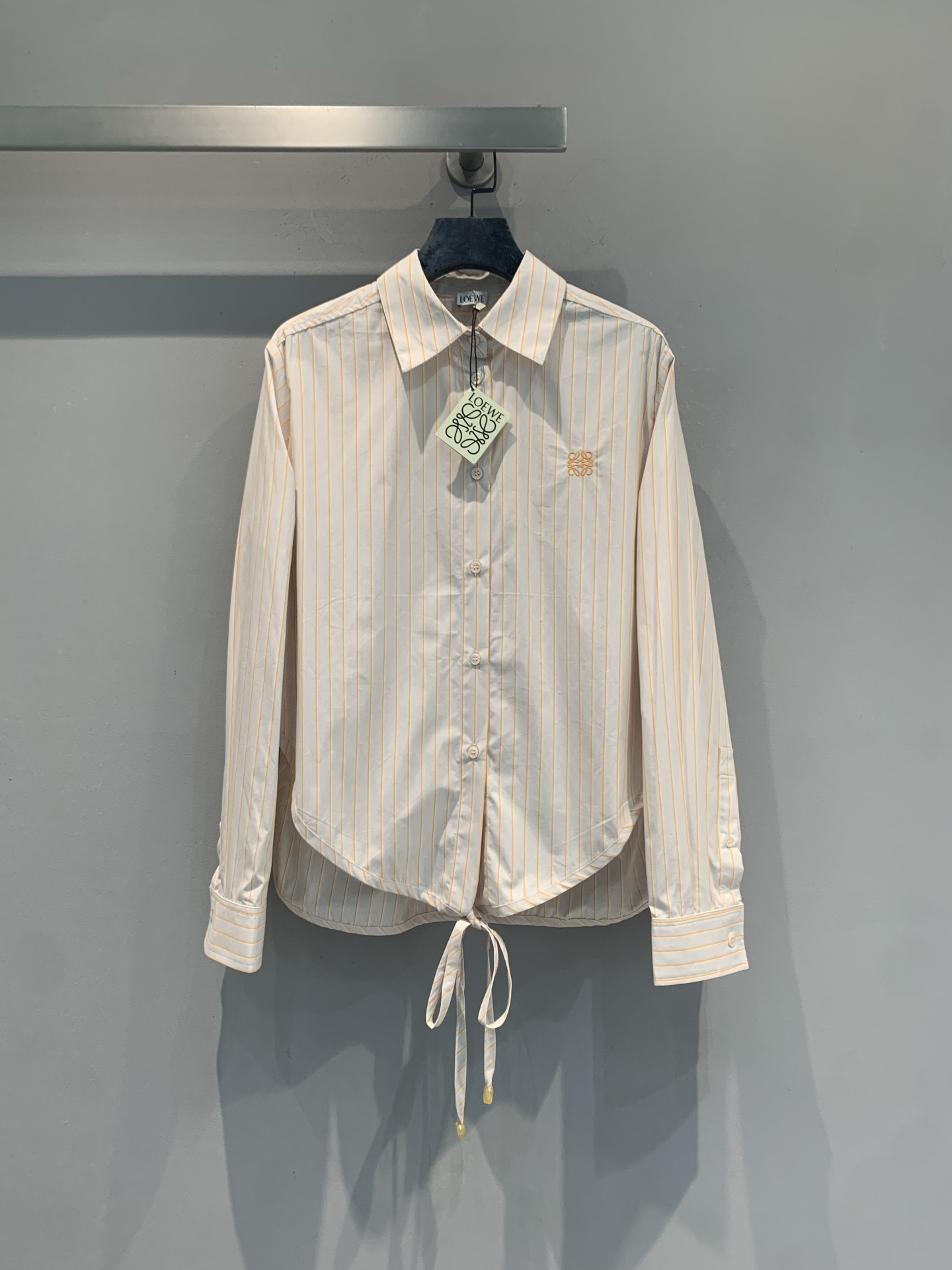 NO:869056,The new model is shipping. The original development Loew* new spring and summer fashionable and versatile embroidered logo striped shirt, pure cotton poplin fabric, soft and breathable, super comfortable to wear!  Off-white base with light orange vertical stripes, and the Anagram embroidery on the chest is very recognizable. The lace-up design at the hem is casual and unique, making it easy to create a smart or relaxed style. It is versatile whether commuting or going out on the weekend ~ Size SML,, loewe, shirts,19860909新款出货啦 原版开发 Loew*春夏新款时髦百搭刺绣logo条纹衬衫,纯棉府绸面料,柔软透气,穿着超舒适！米白底配淡橘竖条纹,胸口Anagram刺绣超有辨识度.下摆系带设计,随性又特别,轻松打造高智感或松弛风穿搭,无论通勤还是周末出街都很百搭哦～码数SML,,loewe,shirts,,Women's clothing
