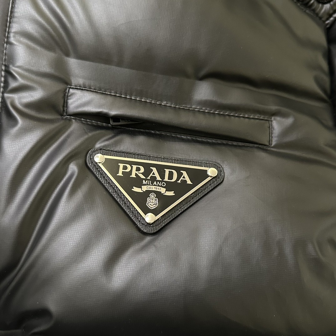 Prada24ss普拉达三角标亮皮连帽羽绒服该款短款派克羽绒采用亮皮面料制成服装满载功能性细节确保温暖呵