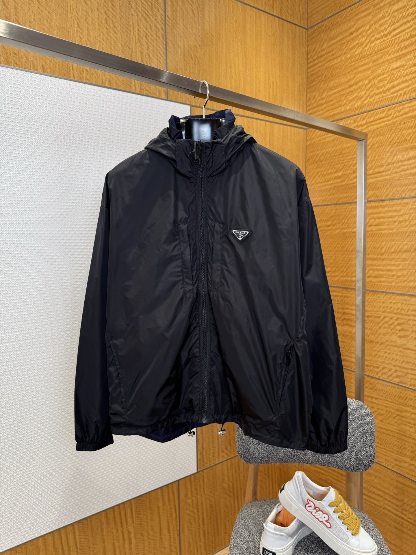 NO:936864,PRADA Reversible Hooded Jacket————————  Made of customized high-density nylon fabric, the yarn is tight, smooth and light to the touch, and has a delicate matte luster; one side is elegant black, with the iconic triangular enamel logo on the chest, low-key but instantly recognizable; the other side is deep navy blue, minimalist and without extras  Decorated, you can switch freely between business travel and urban leisure; the invisible zipper pockets on both sides are convenient for safely storing mobile phones, card holders and keys; the seams on the inside are neat, and the key stress-bearing parts are reinforced with backstitching and hemming technology, so it remains flat and does not scratch your hands even when worn reversely.  ————————8859088 Material nylon Loose fit Color black Size M~3XL,,prada,prada,jackets & coats,hats,19860909PRADA普拉达双面可穿连帽夹克 ——————— 采用定制高密度尼龙面料,纱线紧密、手感顺滑轻盈,自带细腻哑光光泽；一面为典雅黑,胸前点缀标志性三角珐琅Logo,低调却一眼识别；另一面为深邃海军蓝,极简无额外装饰,可在商务出行与都市休闲之间自由切换;两侧隐形拉链口袋便于安全收纳手机、卡包与钥匙；内里缝份整齐,关键受力位采用加固回针与包边工艺,反穿也依旧平整不刮手. ————————8859088 材质尼龙 版型宽松 颜色黑色 尺码M~3XL,,prada,prada,jackets & coats,hats,,Men's clothing