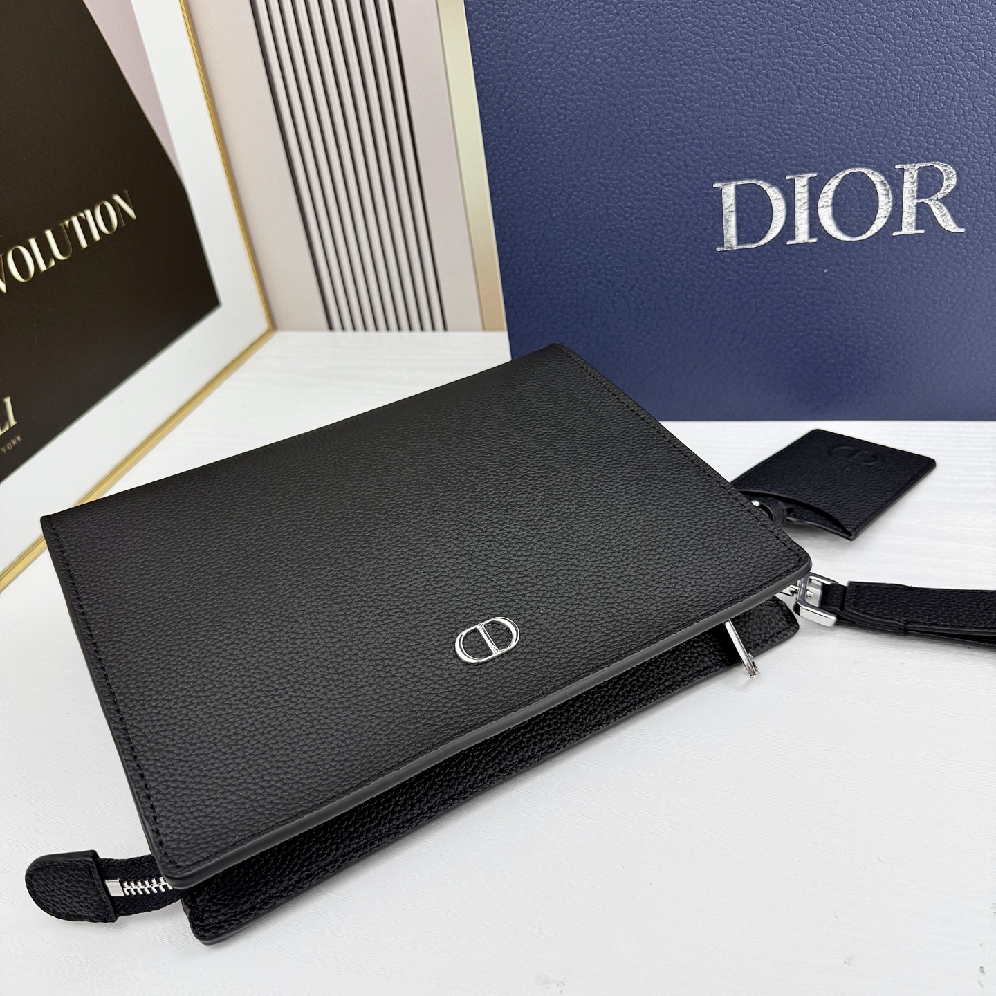 这款 CD Icon A5 三角形手拿包是二零二五冬季男装系列新品，简约的设计彰显 Dior 非凡的精湛
