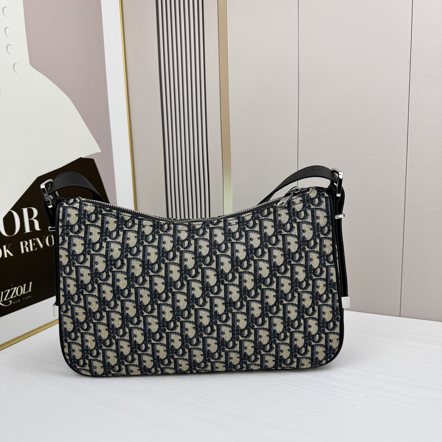 这款 Dior Slider 拉链水饺包是二零二五冬季男装系列新品，高雅时尚。廓形简约柔软，采用黑色 O