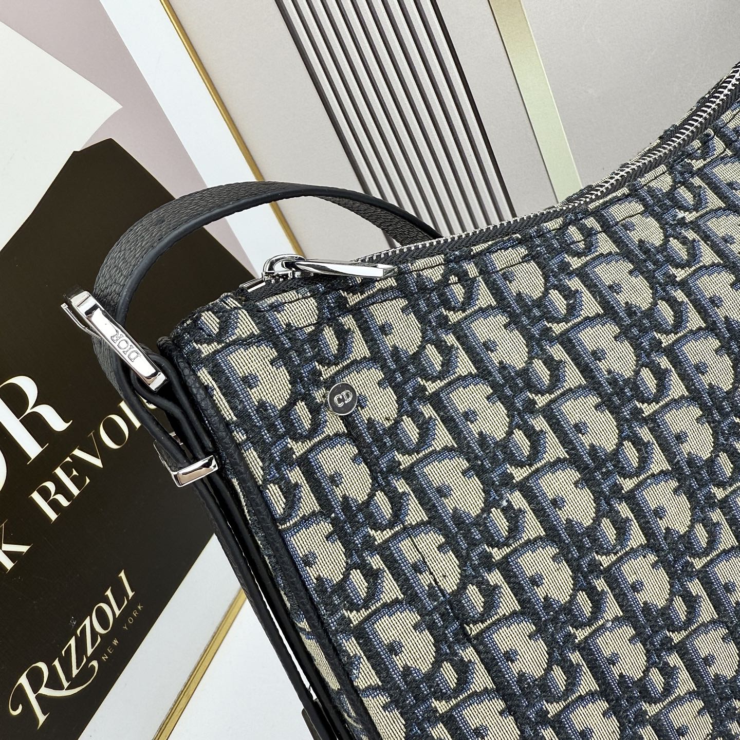 这款 Dior Slider 拉链水饺包是二零二五冬季男装系列新品，高雅时尚。廓形简约柔软，采用黑色 O