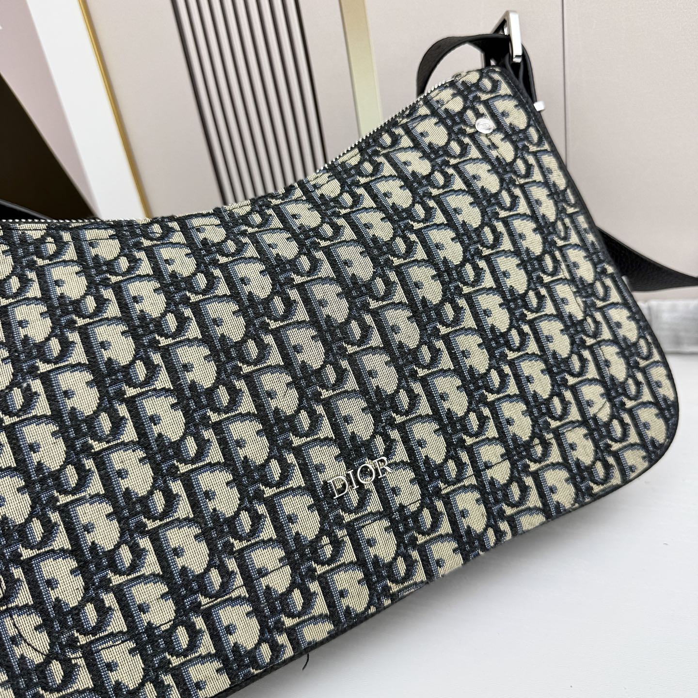 这款 Dior Slider 拉链水饺包是二零二五冬季男装系列新品，高雅时尚。廓形简约柔软，采用黑色 O