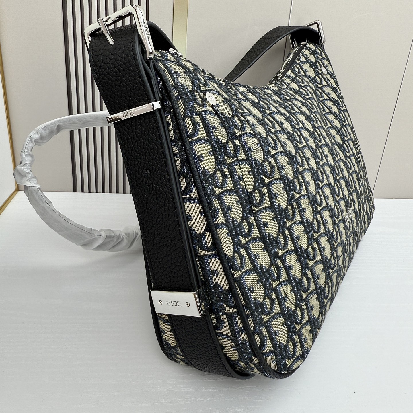 这款 Dior Slider 拉链水饺包是二零二五冬季男装系列新品，高雅时尚。廓形简约柔软，采用黑色 O