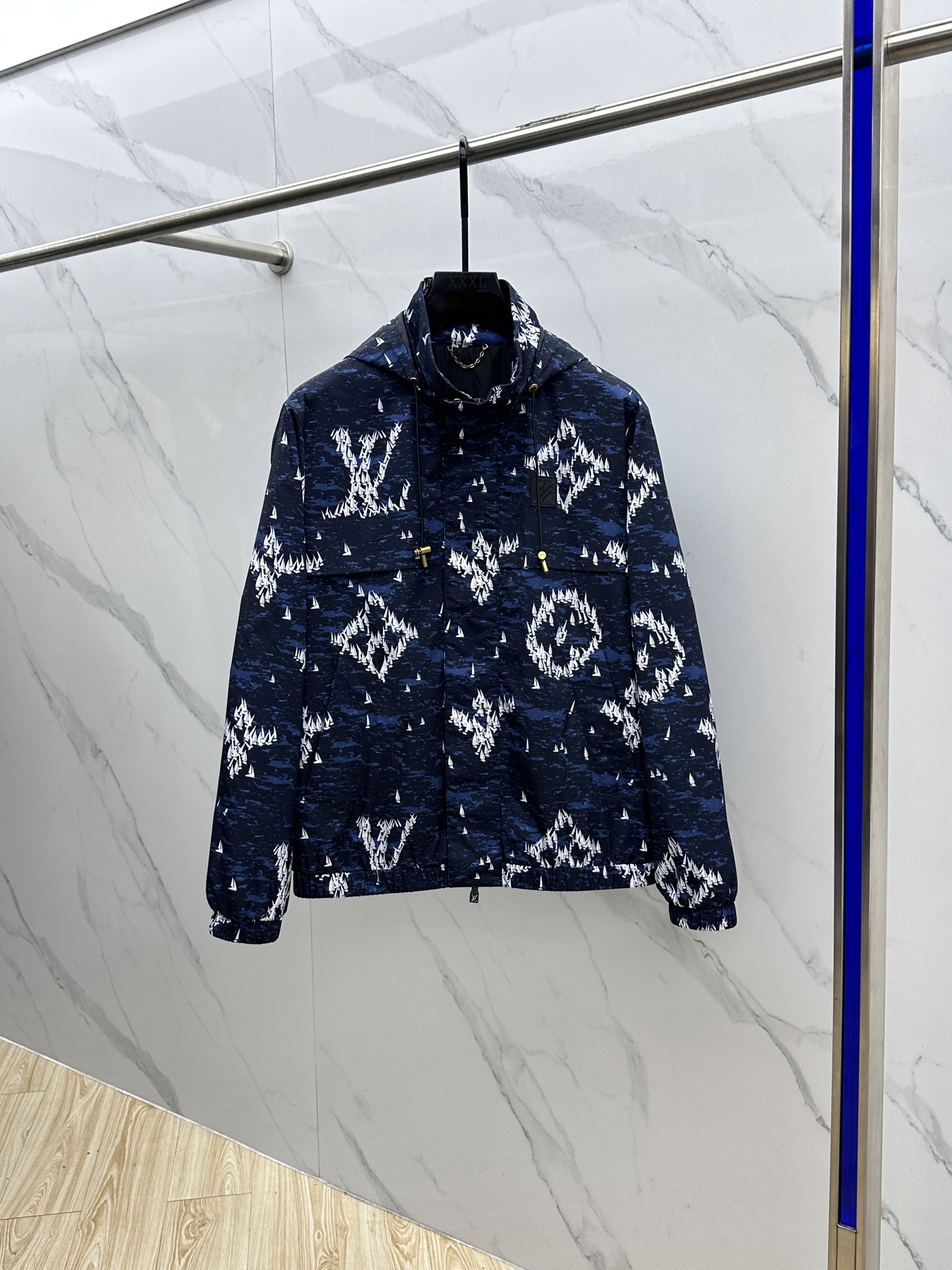 NO:515345,LOUIS VUITTON, Louis Vuitton, is a dark blue sailboat printed nylon hooded with dark blue as the background and is covered with white sailboat printed patterns, which combines fashion and uniqueness. The hooded design is casual and has certain wind and rainproof functions, and is suitable for wearing in various occasions. It is equipped with a drawstring, and the metal pendant at both ends of the drawstring is engraved with the words 'LOUIS VUITTON' to increase brand recognition. There is a black rubber sign on the left chest, with brand letter information imprinted on it, which is low-key and highlights the brand identity. The opening and closing place is a combination of zippers and snaps to increase the firmness of the closure. The zipper head is designed with a simple design, and the snaps also has brand-related marks. There is a large pocket on the front to facilitate the placement of small items. The cuffs and hem are elastic, which can effectively block the cold wind and fit the body.  The inner part is black, the material is smooth, and the skin feels comfortable when worn. In some parts of the inner part, there is also a golden chain decoration. This main material is made of nylon, which is wear-resistant and windproof. It is not easy to pill or damage when worn on a daily basis. It can also play a certain barrier role in the face of light windy weather and keep the body dry. hs digits 48-56,,louis vuitton,louis vuitton,hats,alexander wang19860909LOUIS VUITTON路易威登 深蓝色帆船印花尼龙连帽 以深蓝色为底色,布满白色帆船印花图案,兼具时尚感与独特性. 连帽设计,休闲且具有一定的防风防雨功能,适合多种场合穿着. 配有抽绳,抽绳两端的金属坠饰上刻有“LOUIS VUITTON”字样,增添品牌辨识度. 左胸前位置设有一块黑色橡胶标识牌,上面压印着品牌字母信息,低调又彰显品牌身份. 开合处采用拉链与按扣结合的方式,增加闭合的牢固性,拉链头设计简洁 ,按扣上也有品牌相关印记. 正面设有较大的口袋,方便放置随身小物品. 袖口和下摆处采用松紧设计,能有效阻挡寒风进入,穿着舒适且贴合身形. 内里为黑色,材质顺滑,穿着时皮肤触感舒适.在内里部分位置,还设有金色链条装饰 这款主料采用锦纶,耐磨又防风,日常穿不容易起球、破损,遇到小风天气,也能起到一定阻隔作用,保持身体干爽.hs 码数48-56,,louis vuitton,louis vuitton,hats,alexander wang,Men's clothing