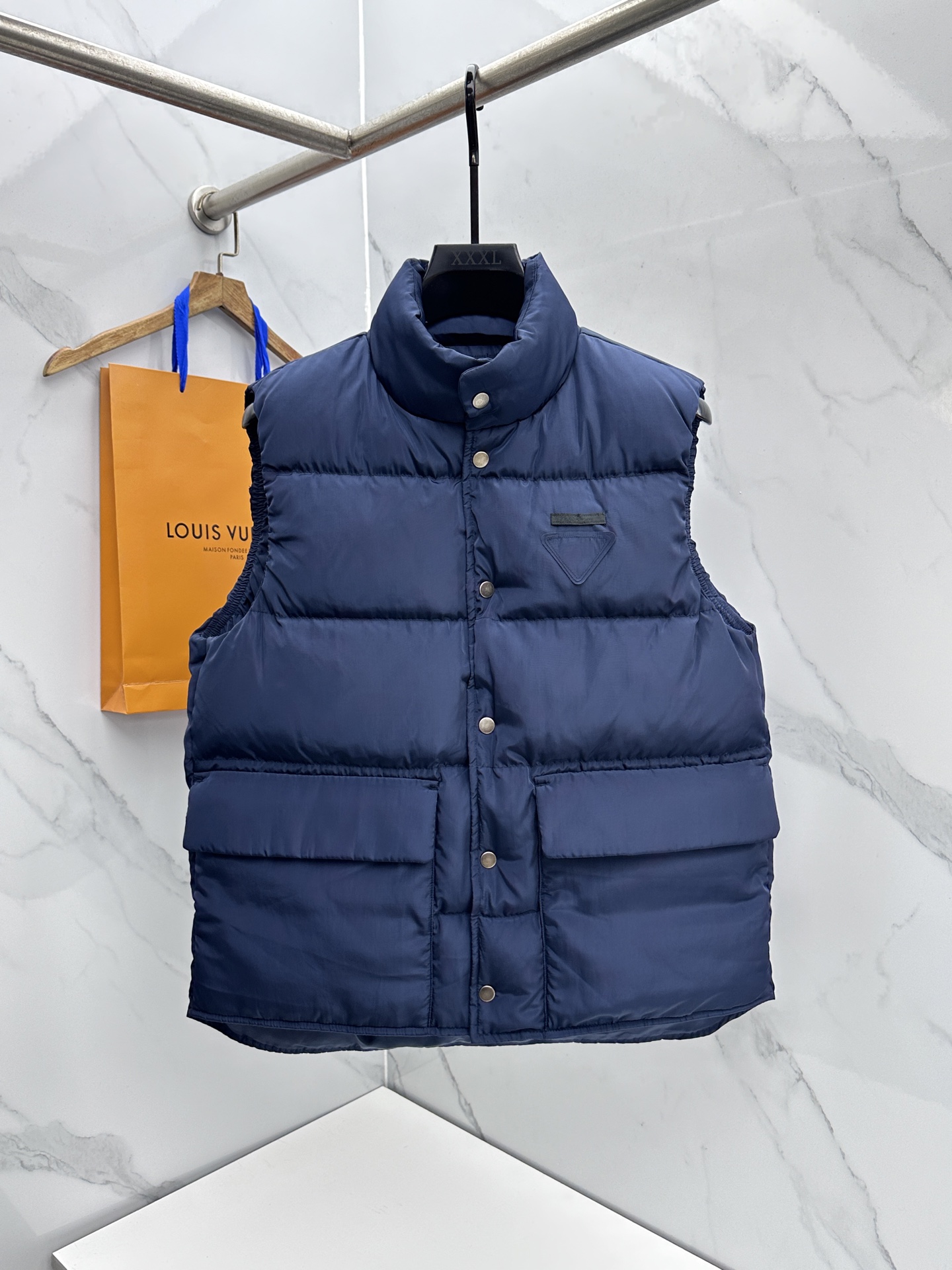 NO:712212,Prada 2025 Autumn and Winter New Down Jacket Show New Down Vest Official Website Synchronization When pioneering design meets the concept of environmental protection, when the luxurious warmth of 90 white goose down embraces the innovation of recycled nylon, this down vest will write a high-end comment for your winter style.  Its silhouette is made of recycled nylon, which not only demonstrates the brand's sustainable fashion attitude, but also gives the fabric excellent wind-resistant and waterproof properties. It is filled with 90% white goose down and 170g of white goose down. It is fluffy and warm like a cloud, building a barrier of warmth for you in the biting cold wind.  The classic stand-up collar design is neat and stylish, and the metal snap buttons and zipper details engraved with the brand logo reveal Prada's exquisite craftsmanship at every turn; the iconic triangle logo is a low-key finishing touch, and the large pockets are both practical and stylish. Whether it is layered with coats to create layers, or worn alone to show personality, you can easily control multiple styles. Complete with A7 three standards!  Size S-XL,,prada,prada,down jacket,19860909Prada普拉达 2025秋冬季新款羽绒服秀场新品羽绒马甲 官网同步 当先锋设计邂逅环保理念,当90白鹅绒的奢暖拥抱再生锦纶的革新,这款羽绒马甲,为你的冬日造型写下高级注解. 它以再生锦纶打造廓形,在彰显品牌可持续时尚态度的同时,赋予面料出色的抗风防水性能；内里填充90白鹅绒,充绒量白鹅绒170克,蓬松暖意如云朵包裹,在凛冽寒风中为你筑起温暖壁垒. 经典立领设计利落有型,金属按扣与镌刻品牌标识的拉链细节,处处流露普拉达的精致工艺；标志性三角徽标低调点睛,大口袋兼具实用性与造型感,无论是叠搭大衣打造层次,还是单穿彰显个性,都能轻松驾驭多元风格.A7三标齐全！ 尺码S-XL,,prada,prada,down jacket,,Men's clothing