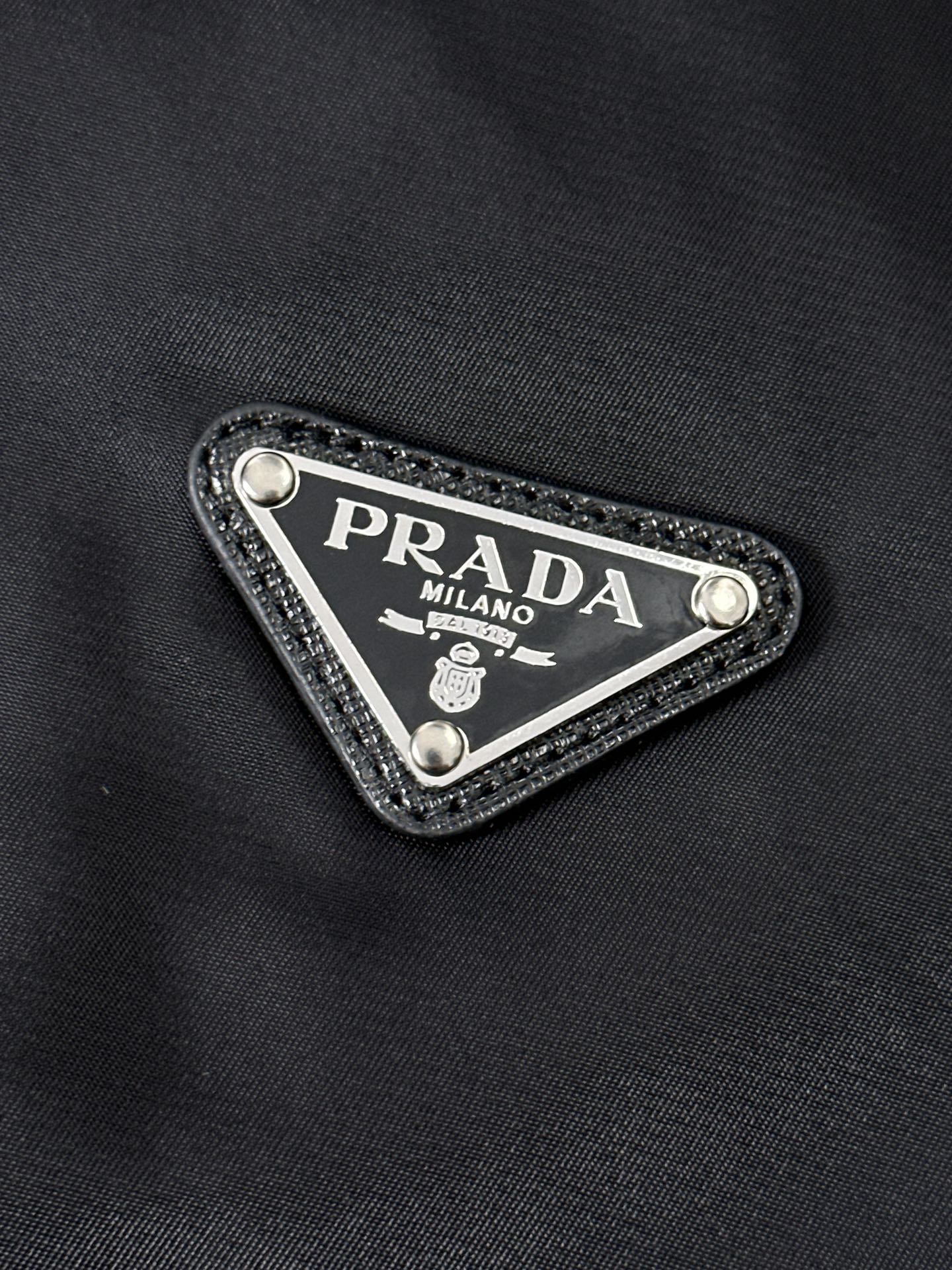 P320  891 PRA……普拉达 春秋季立领夹克！先上先卖，抢占先机。PRADA/普拉达 新品立领风衣外套。这款轻质尼龙夹克配有可拆卸帽和正面拉链，下摆特殊设计，颇具休闲装设计特色。胸前拼接口袋饰有标志性的三角形珐琅徽标，演绎品牌风范。正面拉链式口袋，饰有涂珐琅三角形金属徽标，正面拉链拉合，聚酰胺纤维面料。宝蓝 黑色 尺码：48-56