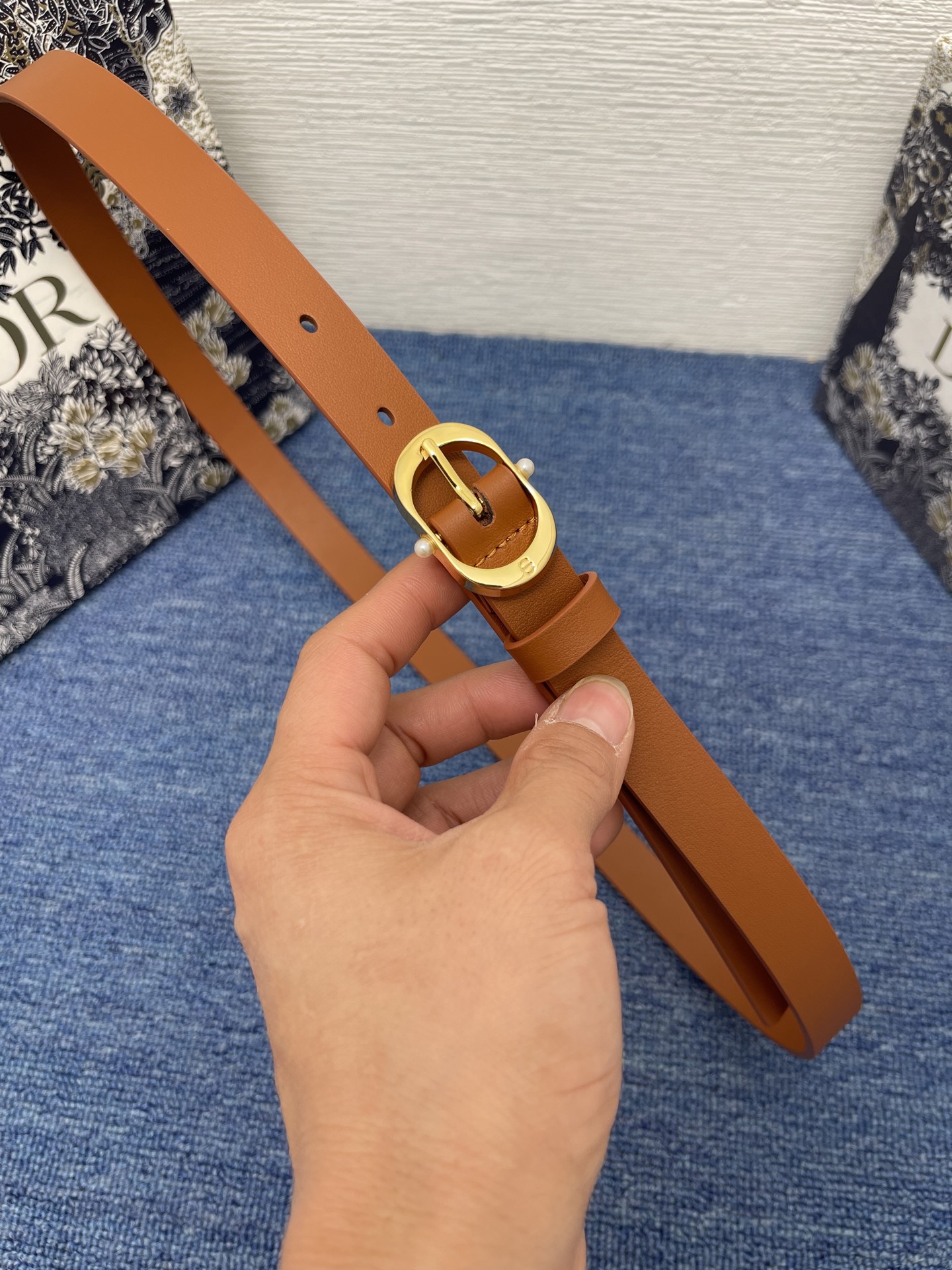 NO:140246,Original Dior Chic Belt 20mm brown smooth cowhide leather No.: B0667UBGO_M900. This Dior Chic Belt is a new product in the spring and summer 2025 ready-to-wear series, highlighting the classic elegance. It is carefully crafted from black smooth cowhide leather and other materials, decorated with a glossy gold finish metal belt buckle to highlight elegant lines, engraved with CD logo and embellished with two white resin beads. Classic elegance, cleverly highlighting the waist curve, and can be matched with jeans, skirts or dresses. Dior Chic Belt buckle engraved with CD logo White resin beads Inside with Christian Dior Paris logo glossy gold finish metal details Cowhide leather, brass, aluminum Made in Italy  Due to technical limitations, product improvement or production batches, the information on the website may have color difference, size error or other detailed errors. The product pictures displayed on the website may be inconsistent with the actual appearance of the product, and the actual product shall prevail. If you have any related questions, please call Dior Customer Service Center., belts, dior, dior, skirts, jeans, cowhide19860909原单 Dior Chic 腰带 20 毫米棕色光滑牛皮革 编号: B0667UBGO_M900. 这款 Dior Chic 腰带是二零二五春夏成衣系列新品,彰显优雅经典.采用黑色光滑牛皮革等材质精心制作,饰以富有光泽的金色饰面金属腰带扣,彰显优雅线条,并镌刻以 CD 标志,点缀以两颗白色树脂珠饰.经典优雅,巧妙突显腰部曲线,可与牛仔裤、半身裙或连衣裙搭配. 镌刻有 CD 标志的 Dior Chic 腰带扣 白色树脂珠饰 内侧饰以 Christian Dior Paris 标志 富有光泽的金色饰面金属细节 牛皮革,黄铜,铝 意大利制造 因技术局限、产品改良或生产批次等原因,网站中的信息可能存在色差、尺码误差或其他细节误差,网站展示的产品图片可能与产品实际外观不一致,以产品实物为准.如有相关问题,请致电迪奥客服中心.,皮带,dior,dior,skirts,jeans,cowhide,Belt