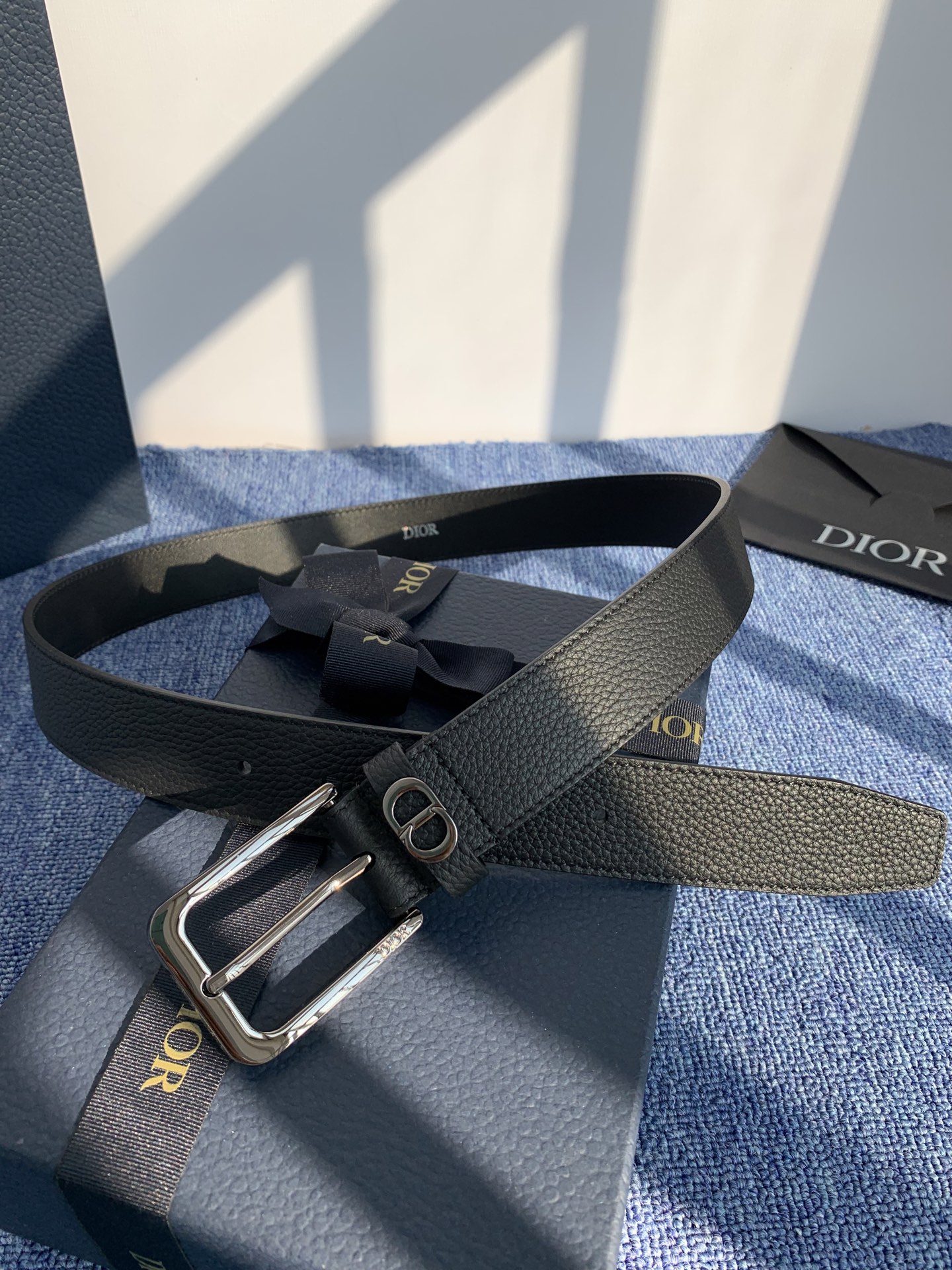 采用黑色粒面牛皮革精心制作，饰以镌刻有 Dior 的针扣和黑色金属覆层铜合金 CD Icon 标志腰带环