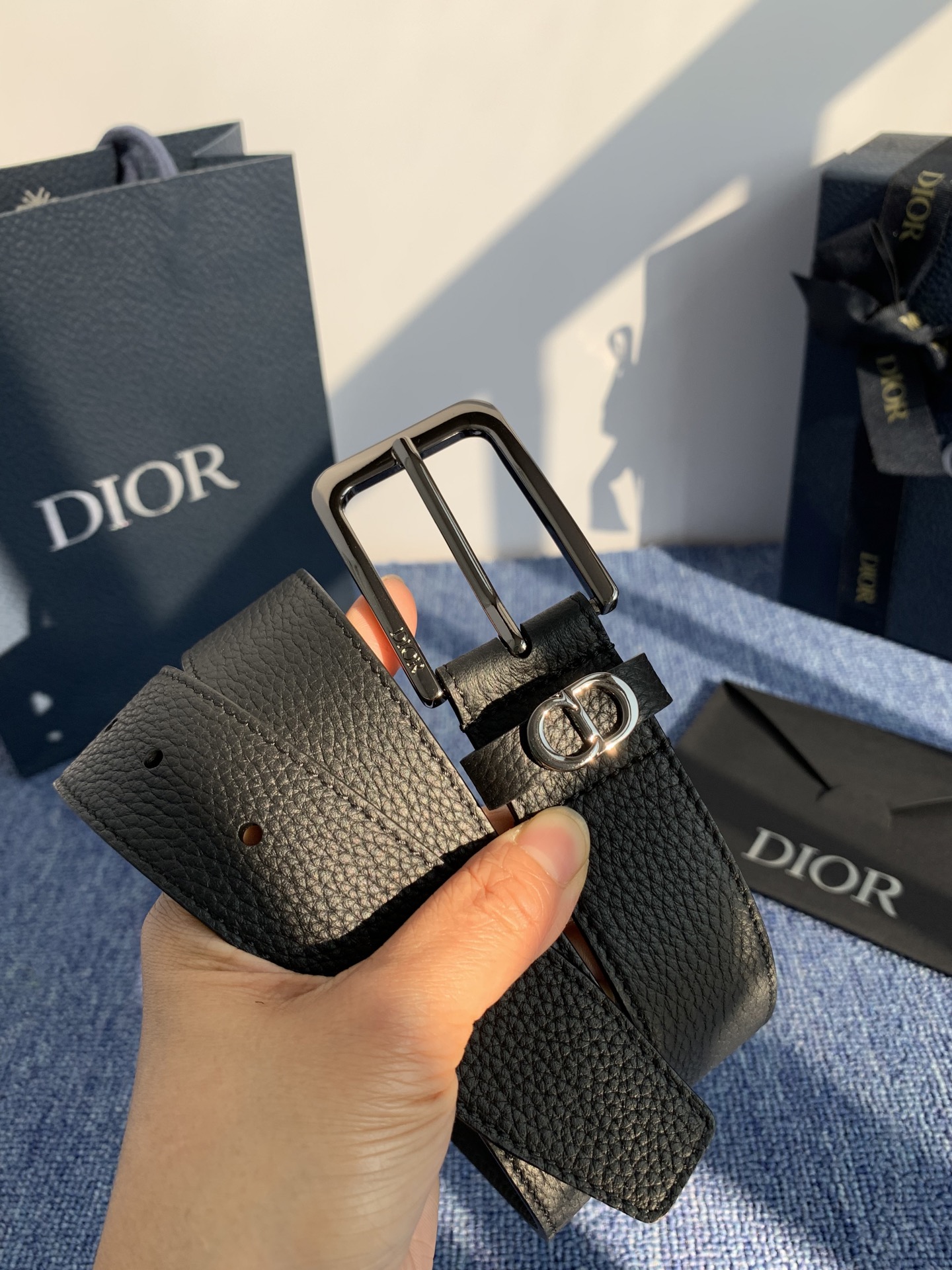 采用黑色粒面牛皮革精心制作，饰以镌刻有 Dior 的针扣和黑色金属覆层铜合金 CD Icon 标志腰带环